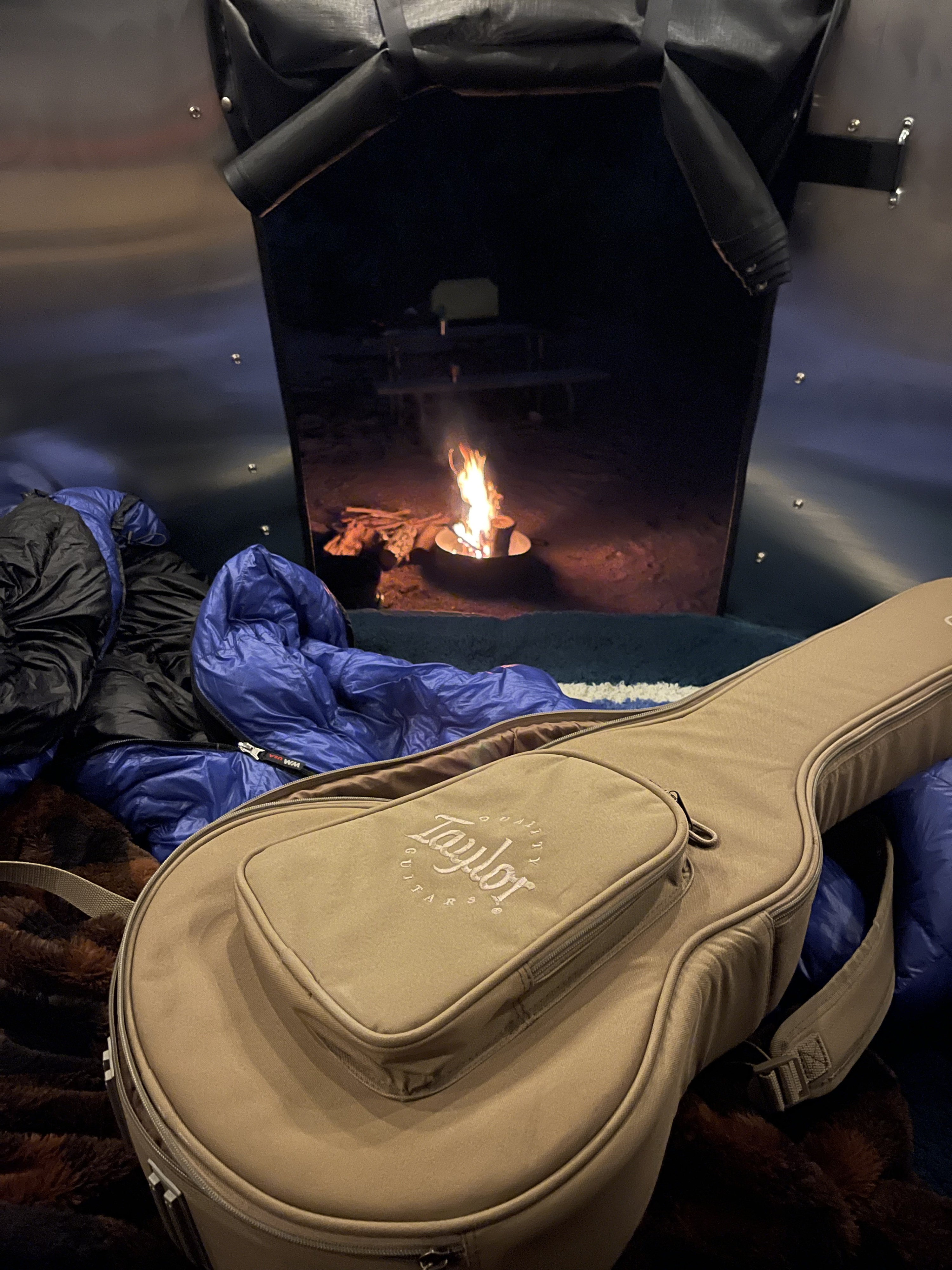 Cozy RV rental setup: guitar ready for fireside tunes, sleeping bags inside, a warm campfire outside.. Airstream Basecamp 2021
