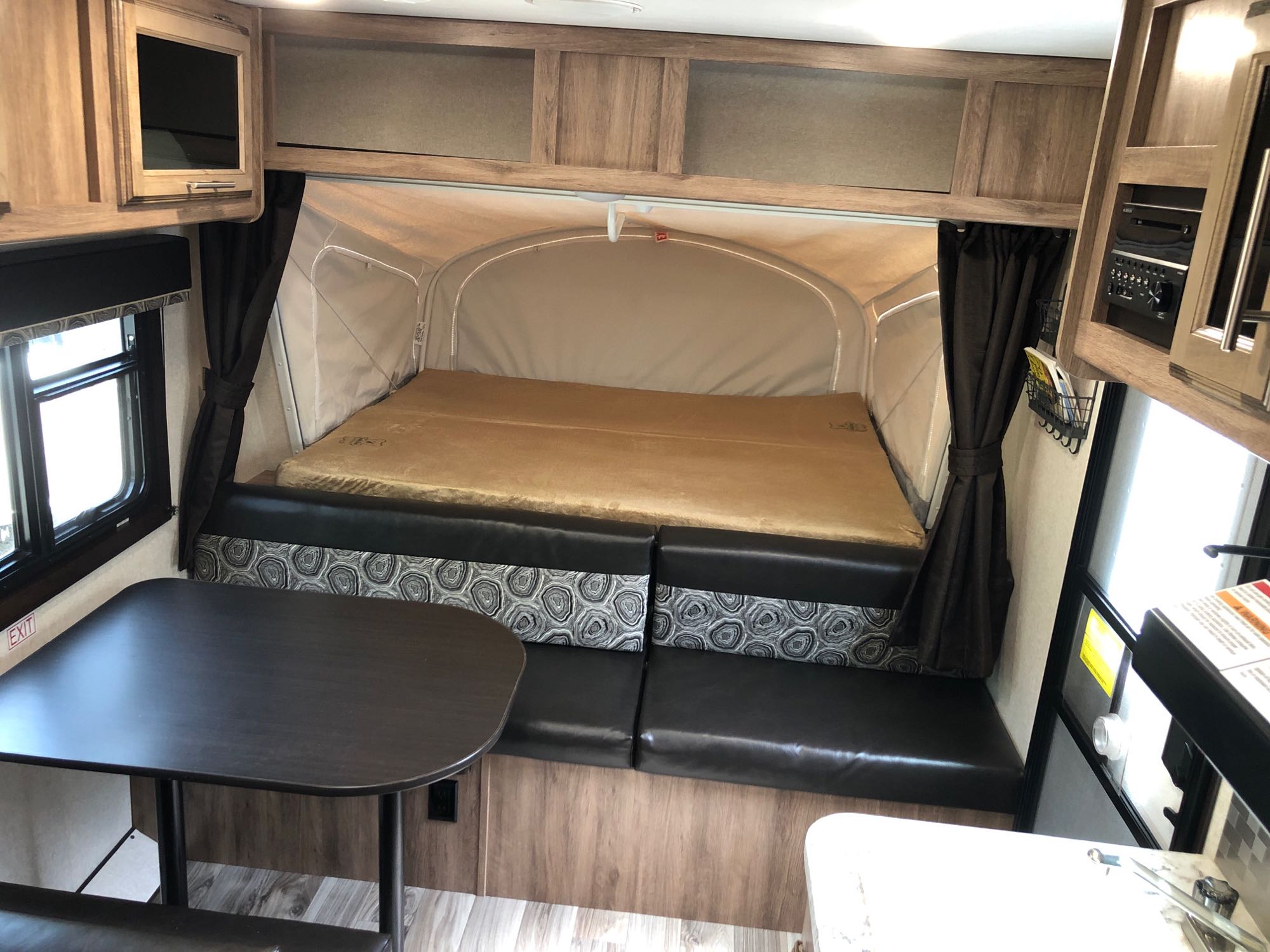 View of an rv rental interior: cozy pop-out bed, convertible dinette, overhead cabinets. Ready for your travel adventures!. Jayco Jay Feather 2018