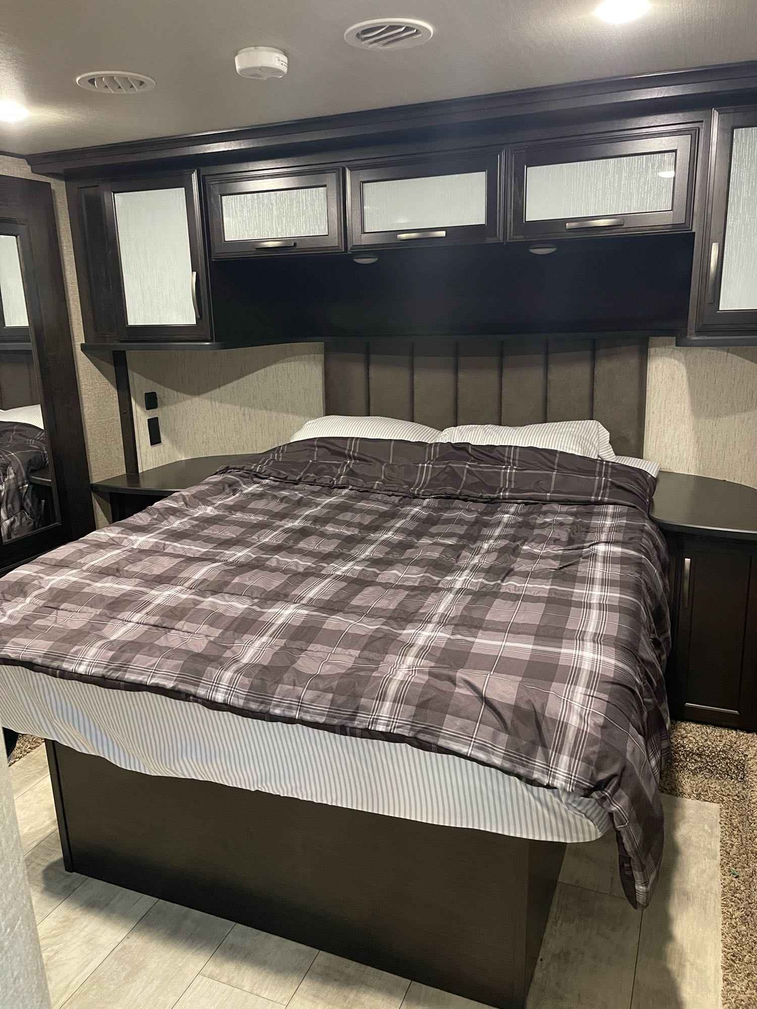 Comfortable RV rental bedroom with plaid bedding, built-in storage, and modern finishes for your travels.. Grand Design Momentum Toy Hauler 2019