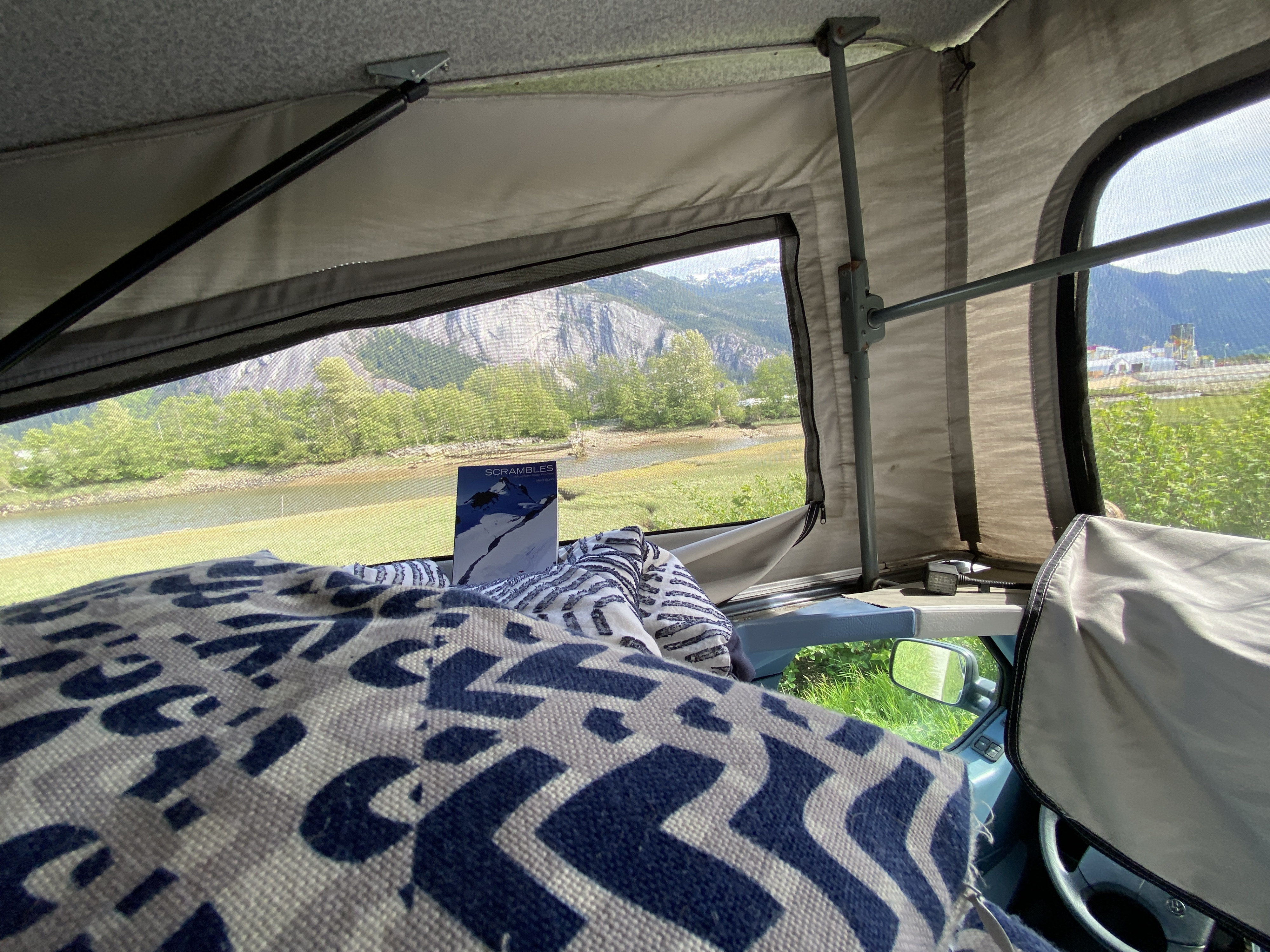 Cozy RV rental interior with a mountain view and river. A "Scrambles" book for adventure planning.. Volkswagen Westfalia 1992
