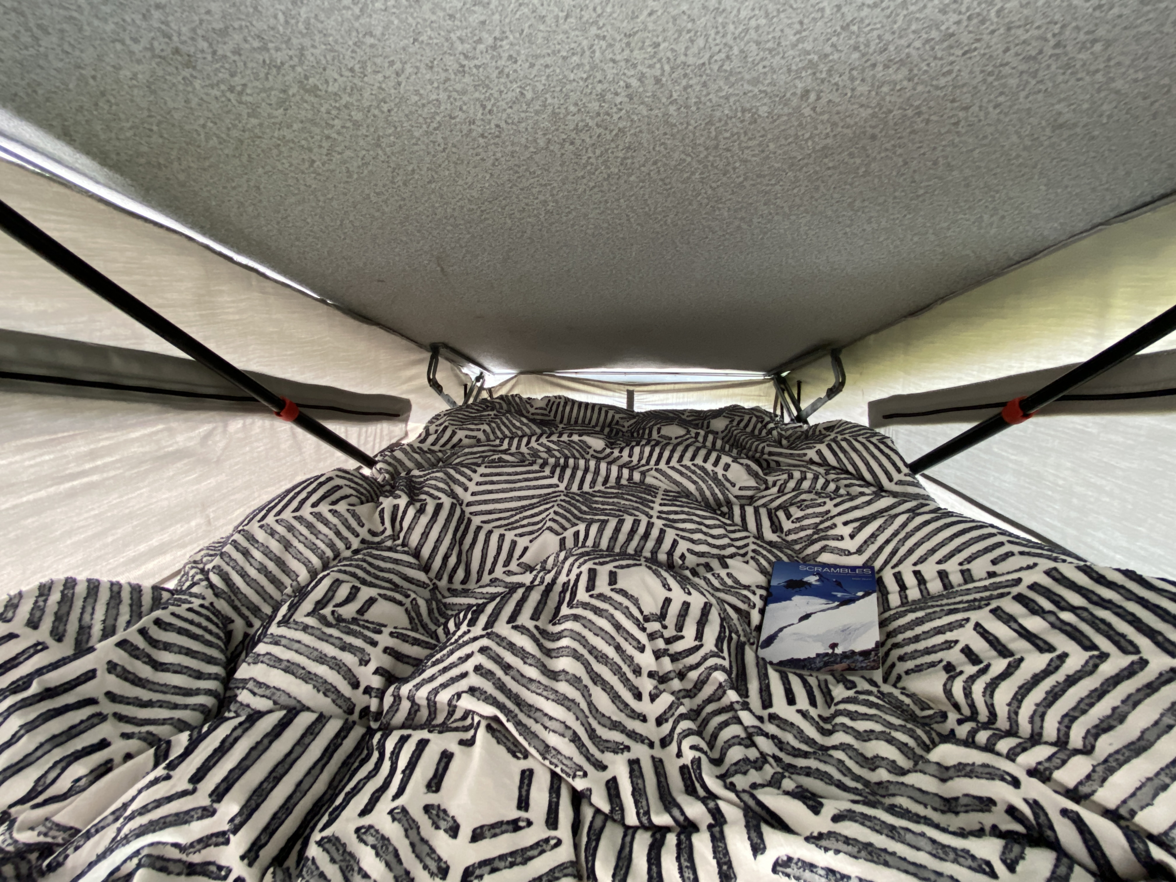 Cozy RV rental pop-top camper interior with a patterned bed and book, ideal for comfortable camping.. Volkswagen Westfalia 1992