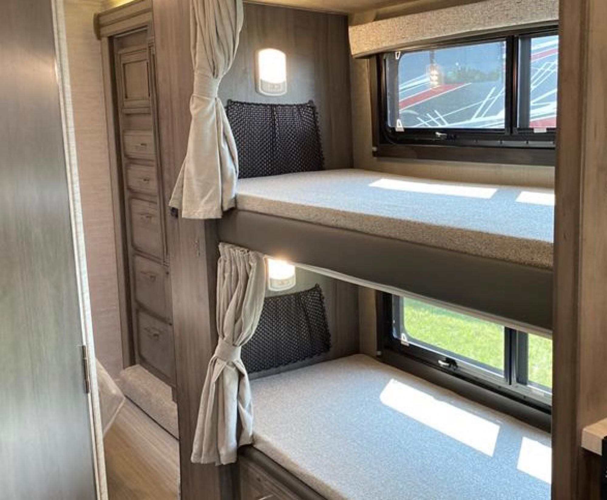 Inside an RV rental: two bunk beds with window views, wall lights, and storage cabinetry.. Entegra Coach Odyssey 2022