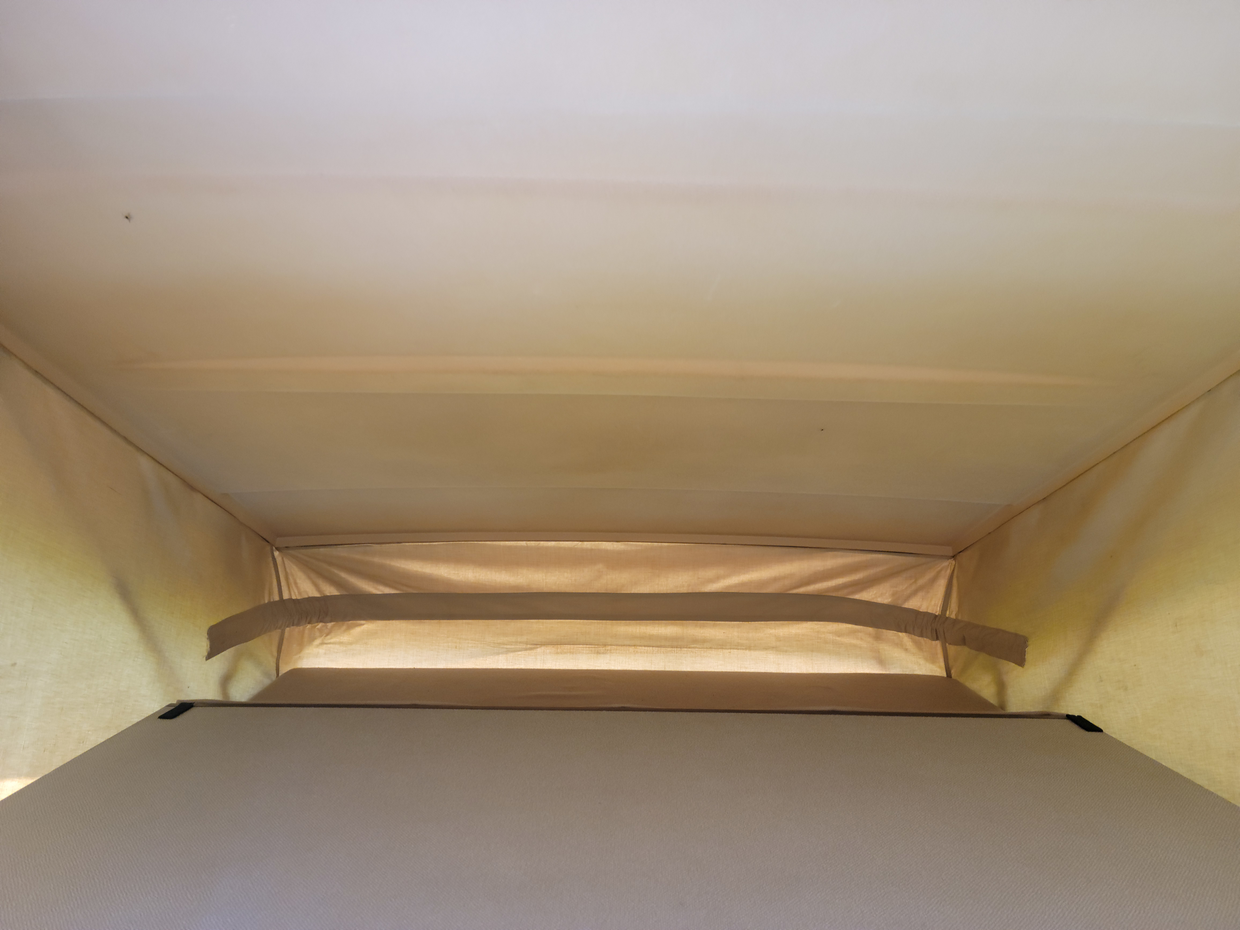 Interior of a pop-top RV rental, showcasing the airy fabric sleeping tent and comfortable bed platform for camper adventures.. Volkswagen Westfalia 1986