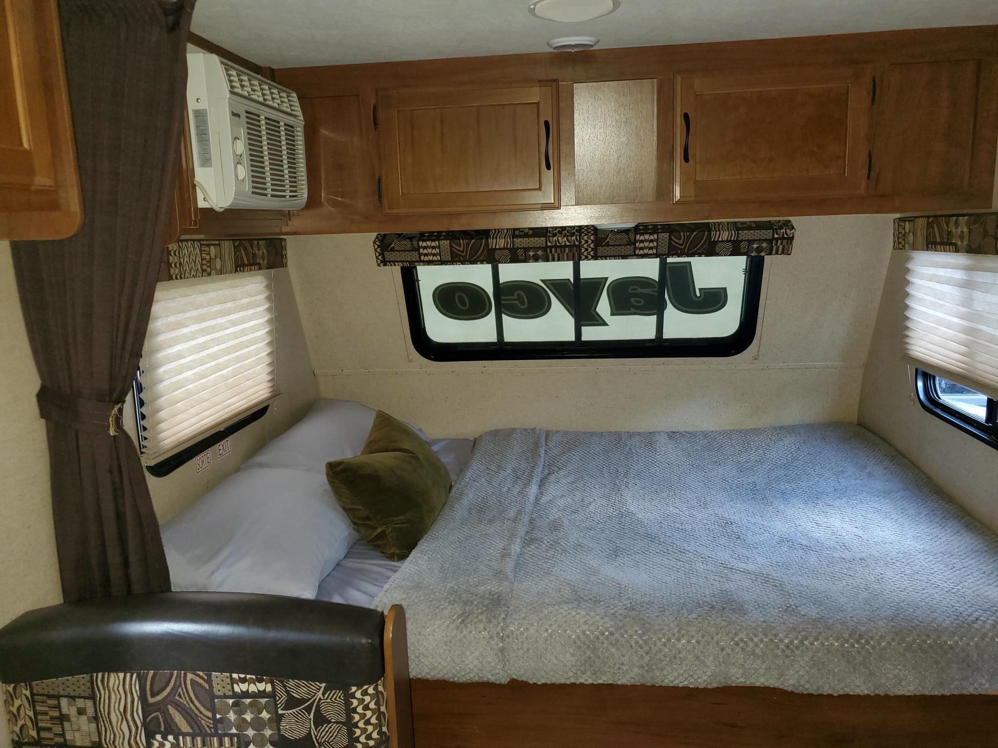 Cozy RV rental bedroom with comfortable bed, overhead cabinets, and AC.. Jayco Jay Flight SLX 2016