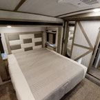 Spacious bedroom of an RV rental, featuring a large bed with a padded headboard and mirrored closet doors. Perfect for comfortable travel.. Forest River Wildwood Heritage Glen 2022
