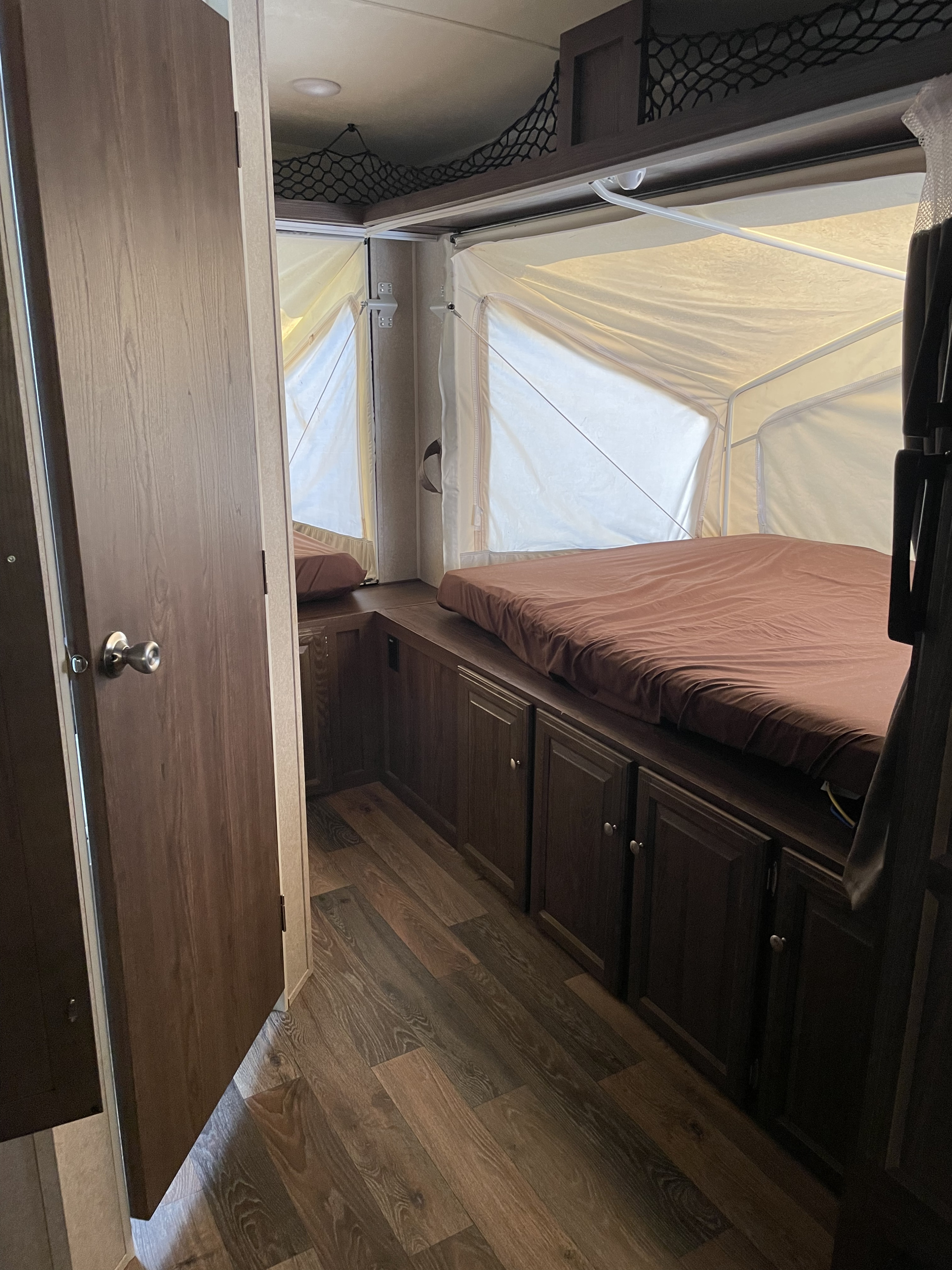 Cozy pop-up camper RV rental interior, showing beds, cabinets, and wood flooring. Ideal for your next adventure.. Forest River Rockwood Roo 2016