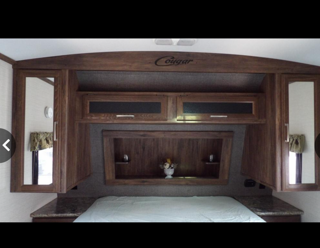 RV rental bedroom: Compact, featuring a bed, wooden overhead cabinets, mirrored closets, and built-in storage.. Keystone RV Cougar X-Lite 2015