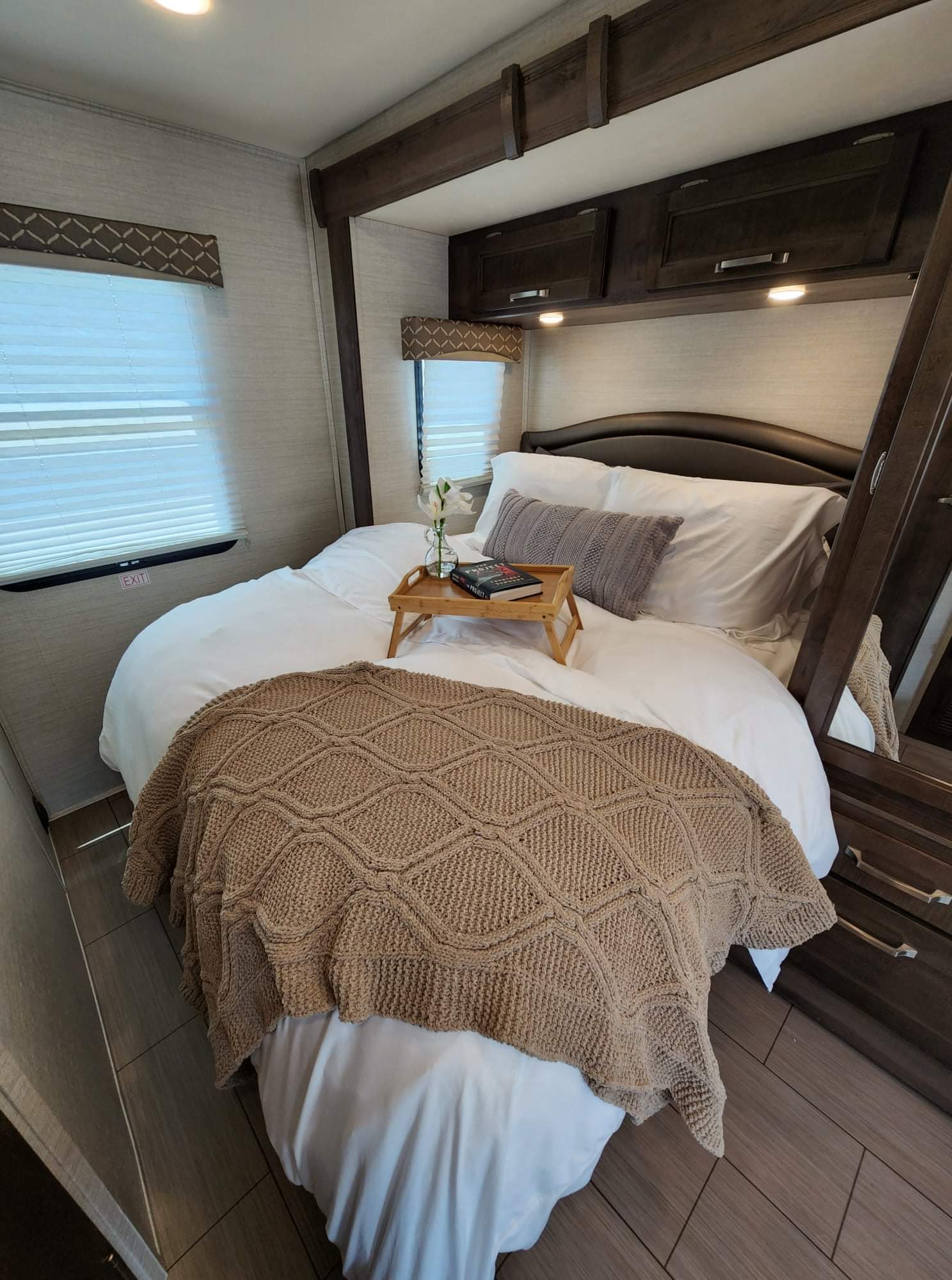 Step into comfort: a cozy RV rental bedroom with white bedding, a knit throw, windows, and overhead storage.. Jayco Melbourne 2019