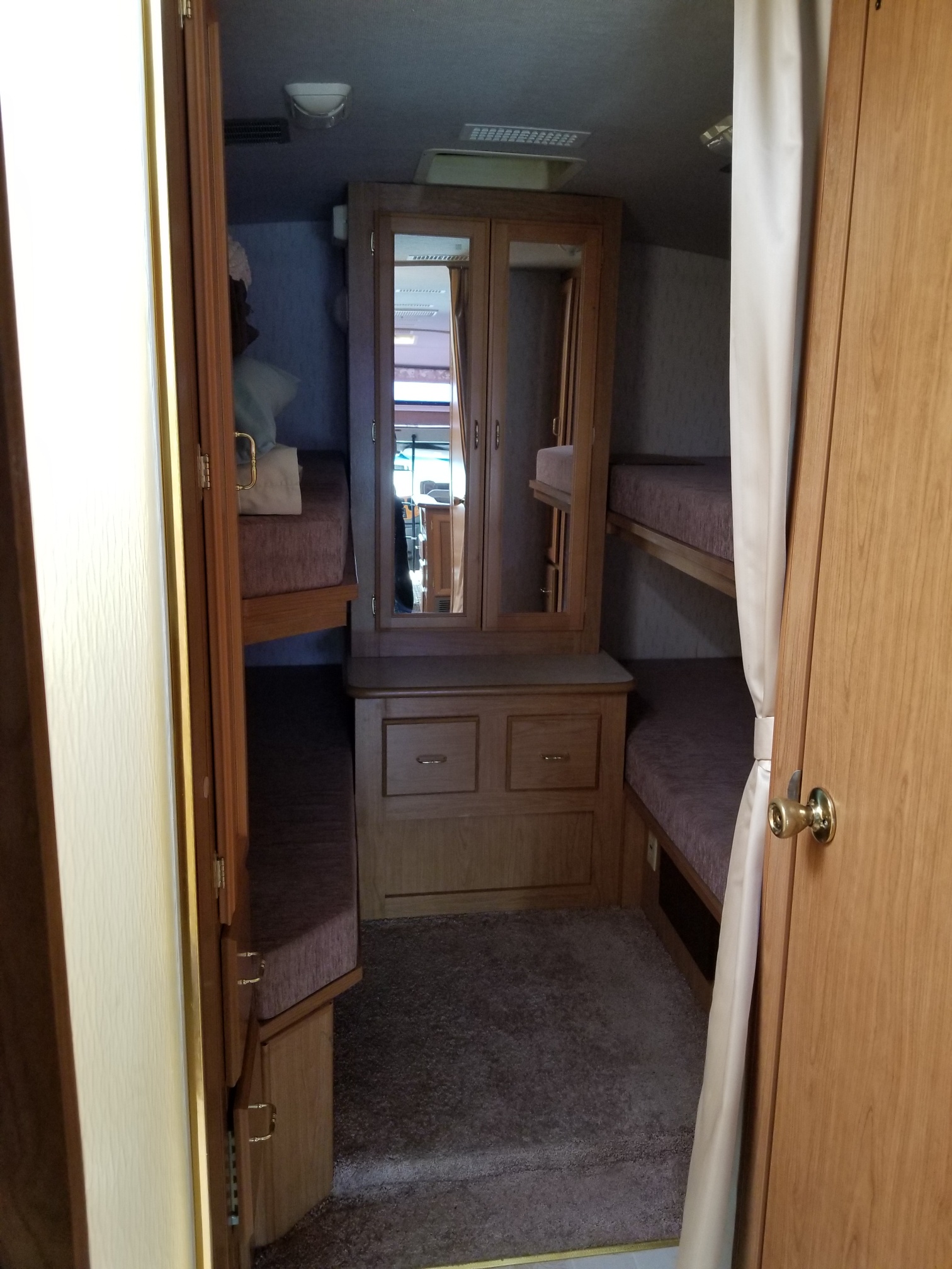 Cozy RV rental interior featuring bunk beds and a central cabinet, perfect for family adventures.. Ford Tioga 1998
