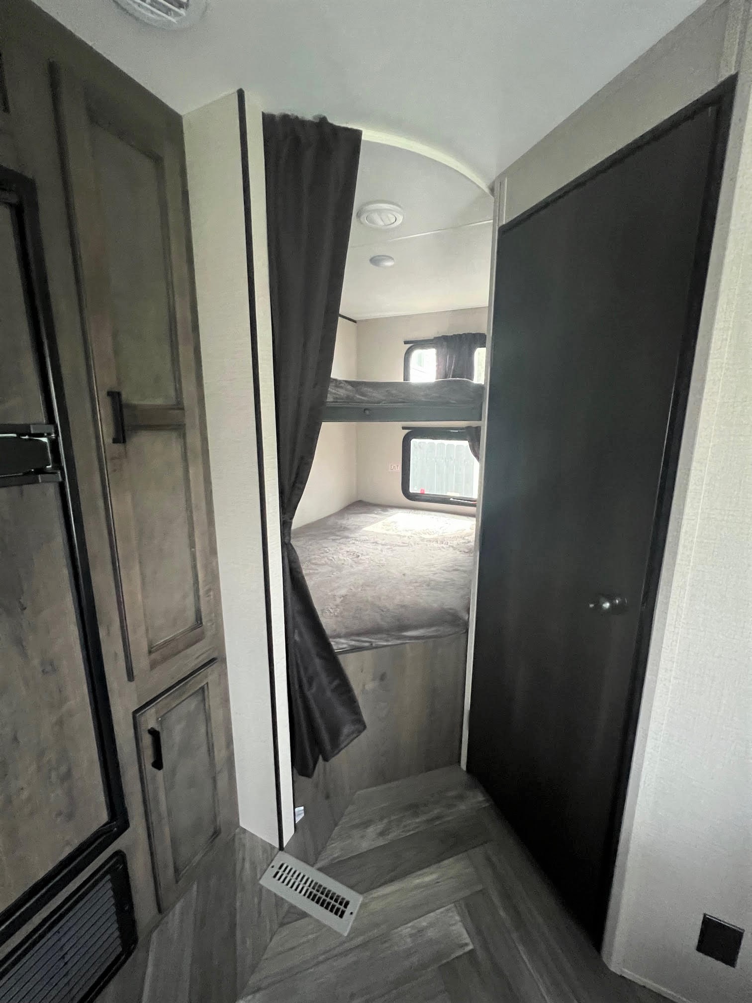 Cozy RV rental interior with bunk beds, privacy curtain, and compact amenities. Perfect for family adventures.. Highland Ridge Open Range Olympia 2022