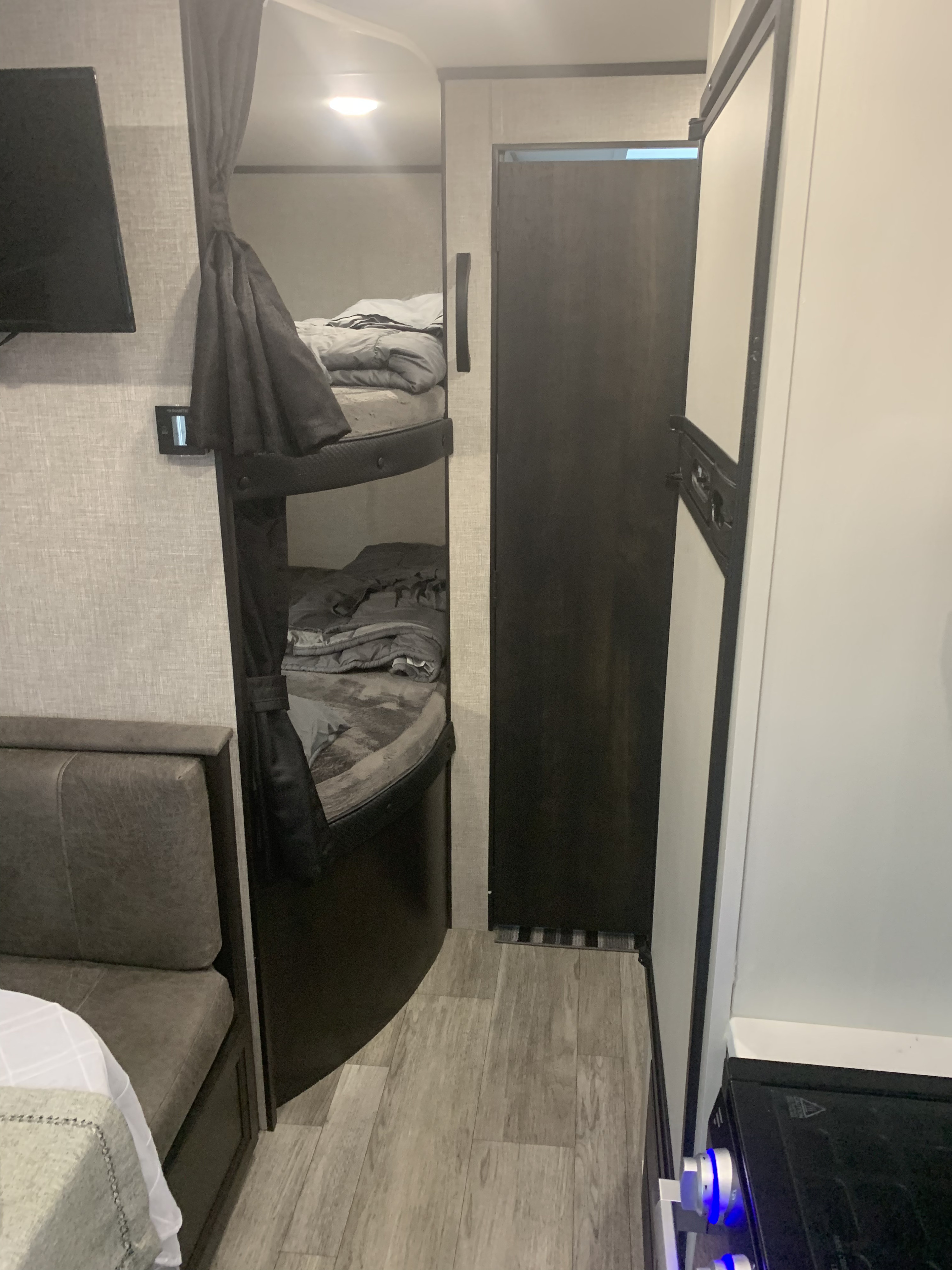 Cozy RV rental interior with bunk beds, a dining booth, and a compact kitchen including a fridge and stove.. Jayco Jay Flight 2022