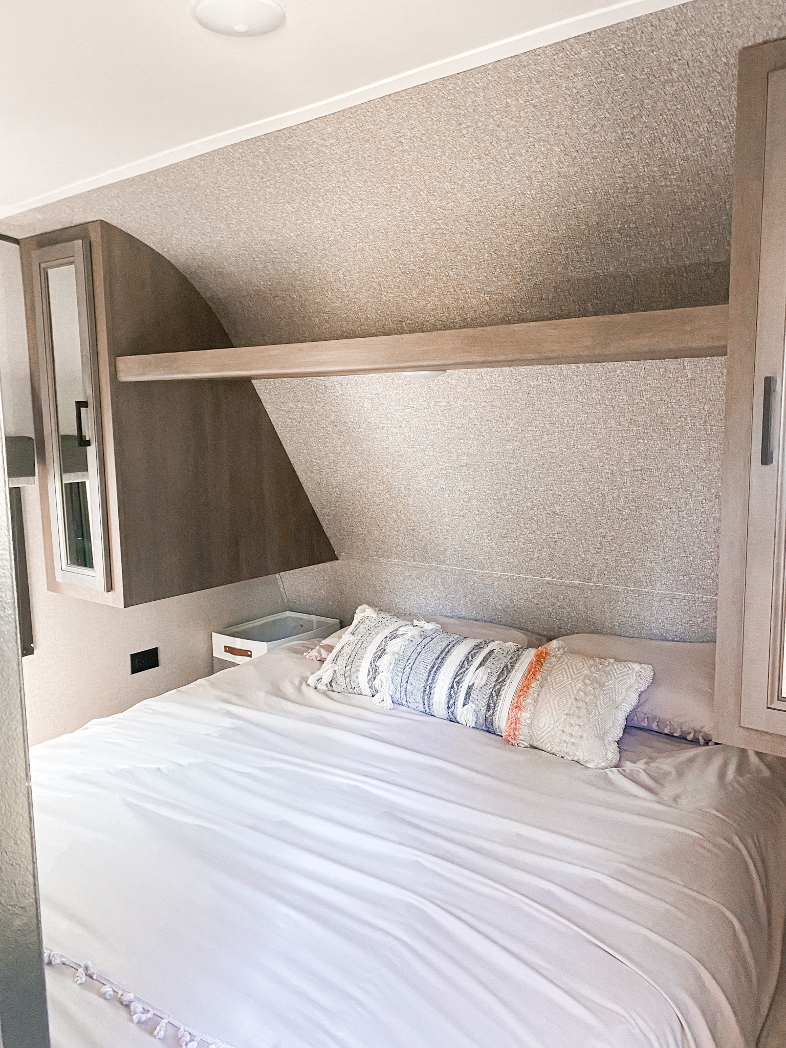 Cozy RV rental bedroom with a comfy bed, patterned pillows, textured walls, and practical overhead storage.. Starcraft Travel Trailer 2022