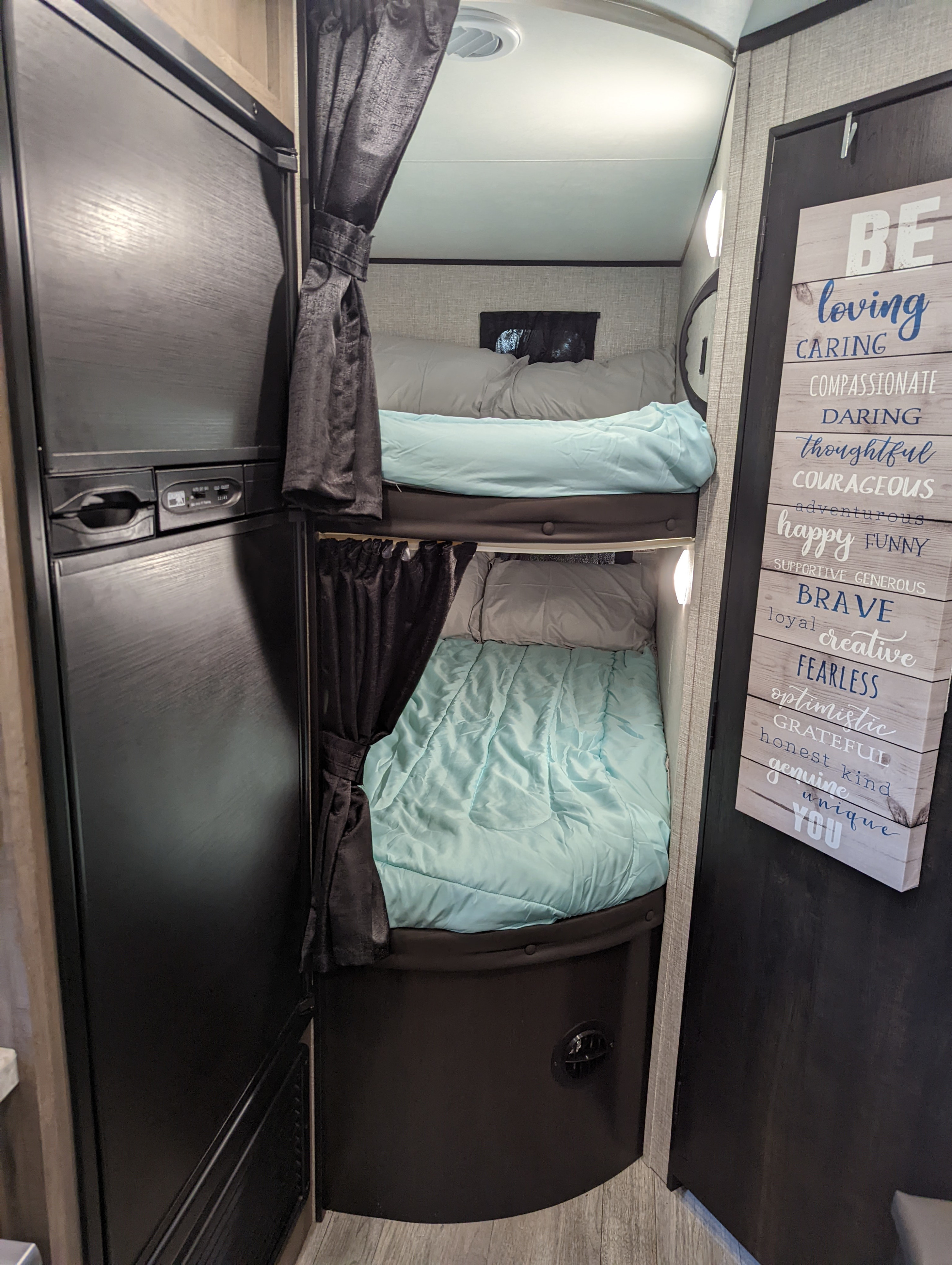 Cozy RV rental interior featuring comfortable bunk beds, a refrigerator, and an inspiring decorative sign.. Jayco 224BHW 2022