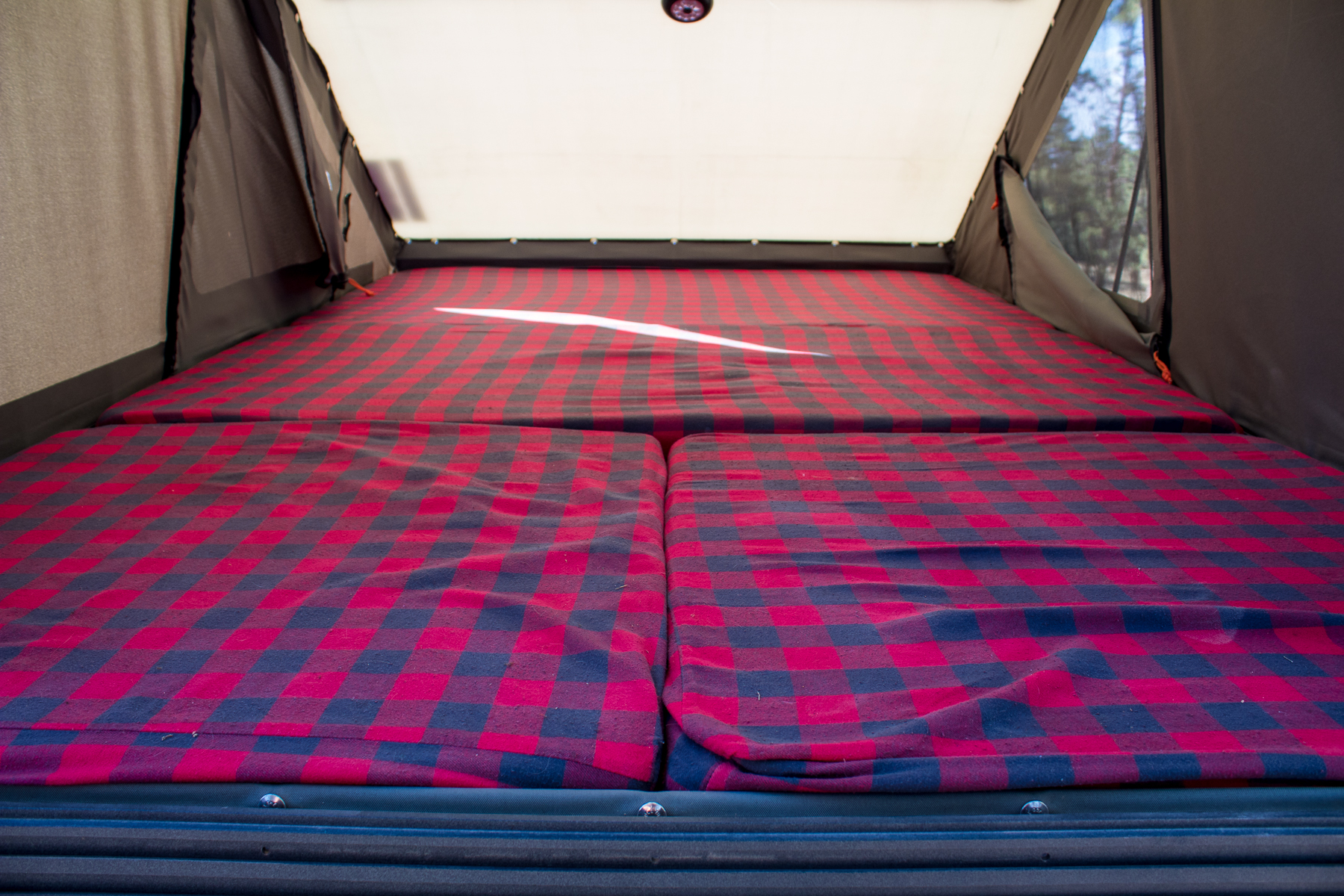 Inside an RV rental: Red and black plaid mattresses in a cozy tent bed, perfect for camping.. Ram Power Wagon 2020