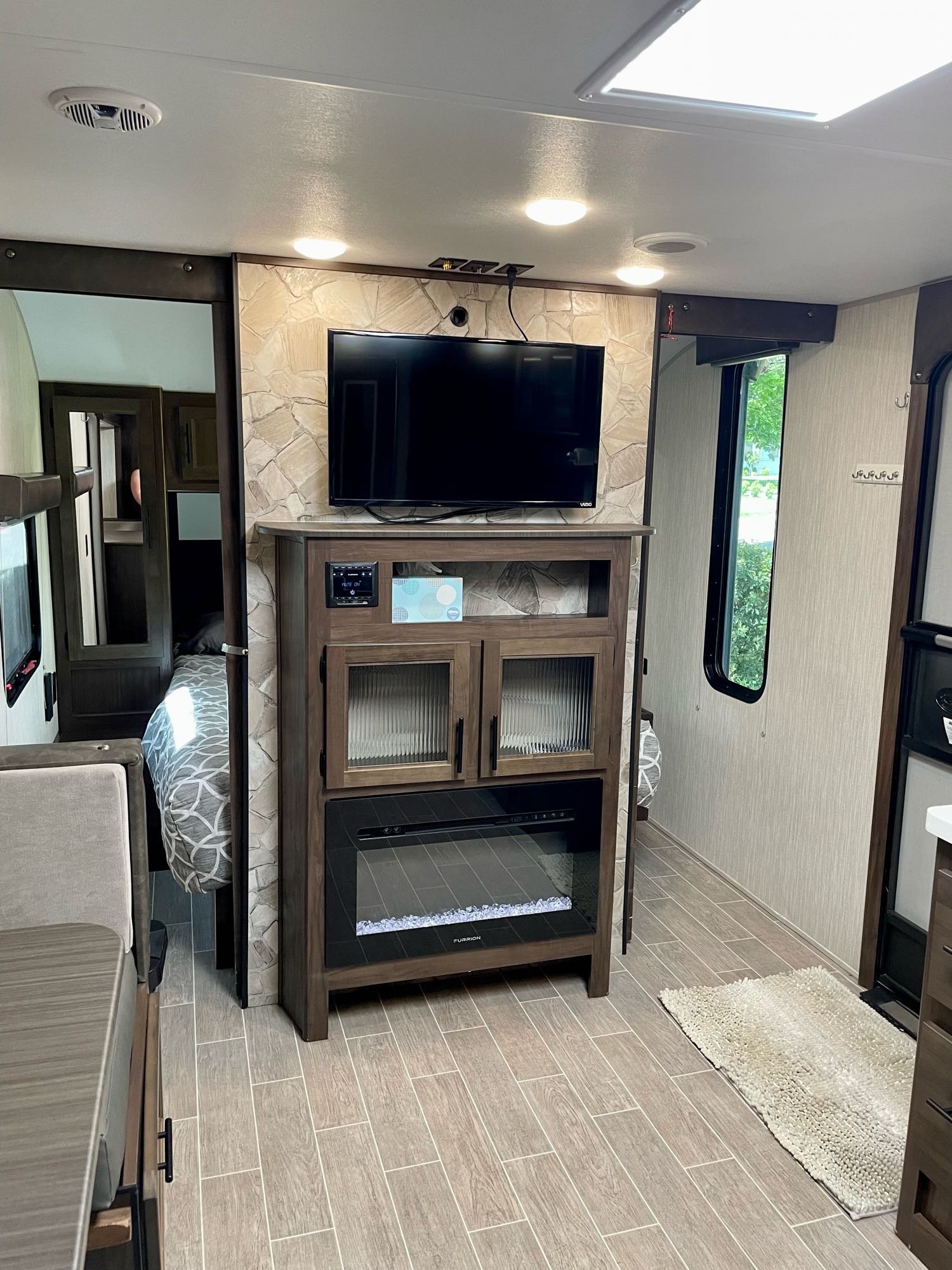 Cozy RV rental interior with a stone-accented living room, TV, fireplace, dinette, and visible bedroom.. Forest River Cherokee Grey Wolf Black Label 2020
