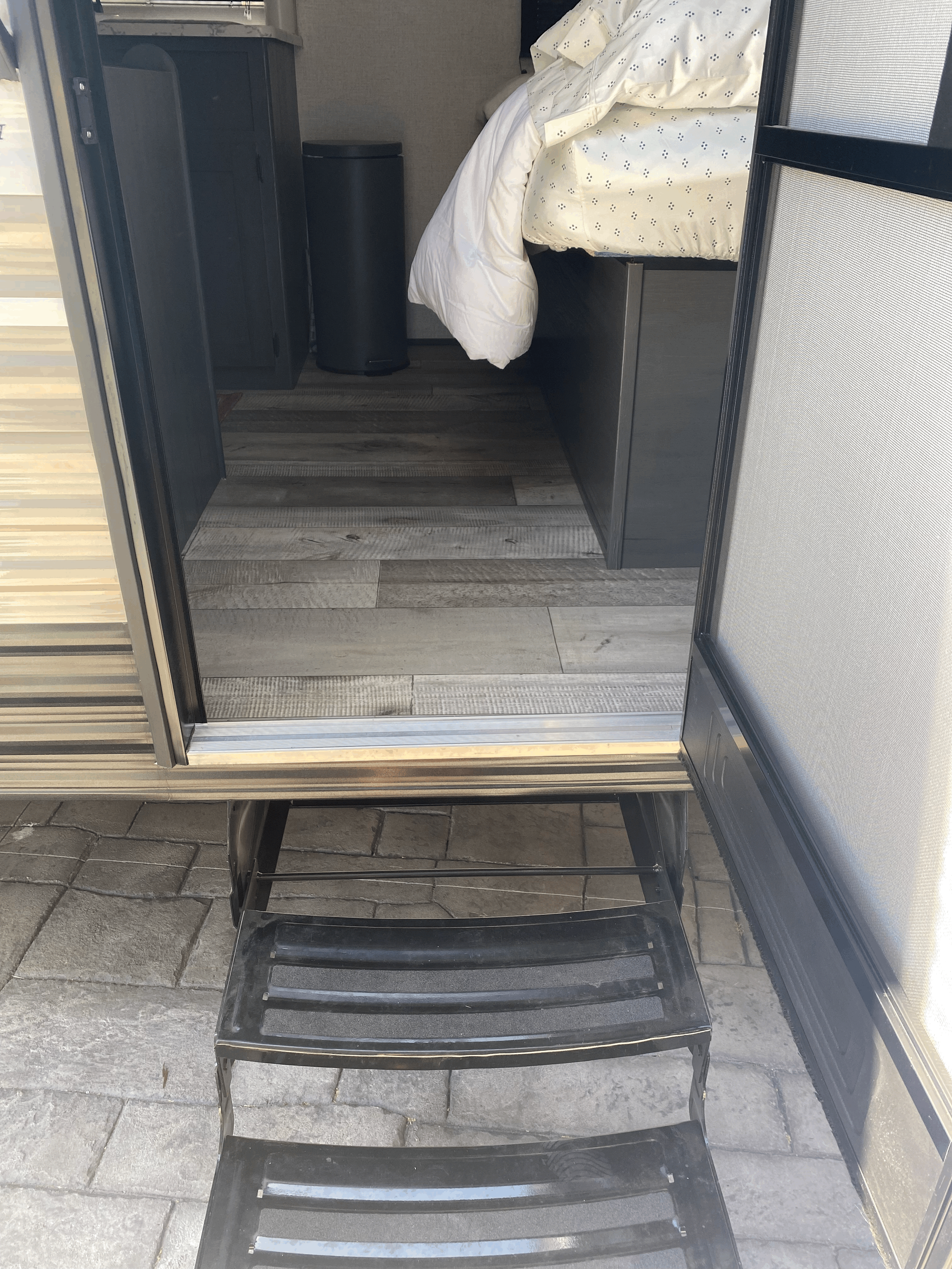 Open door of an RV rental revealing its interior, including steps, wood flooring, and bedroom area.. Dutchmen Other 2021