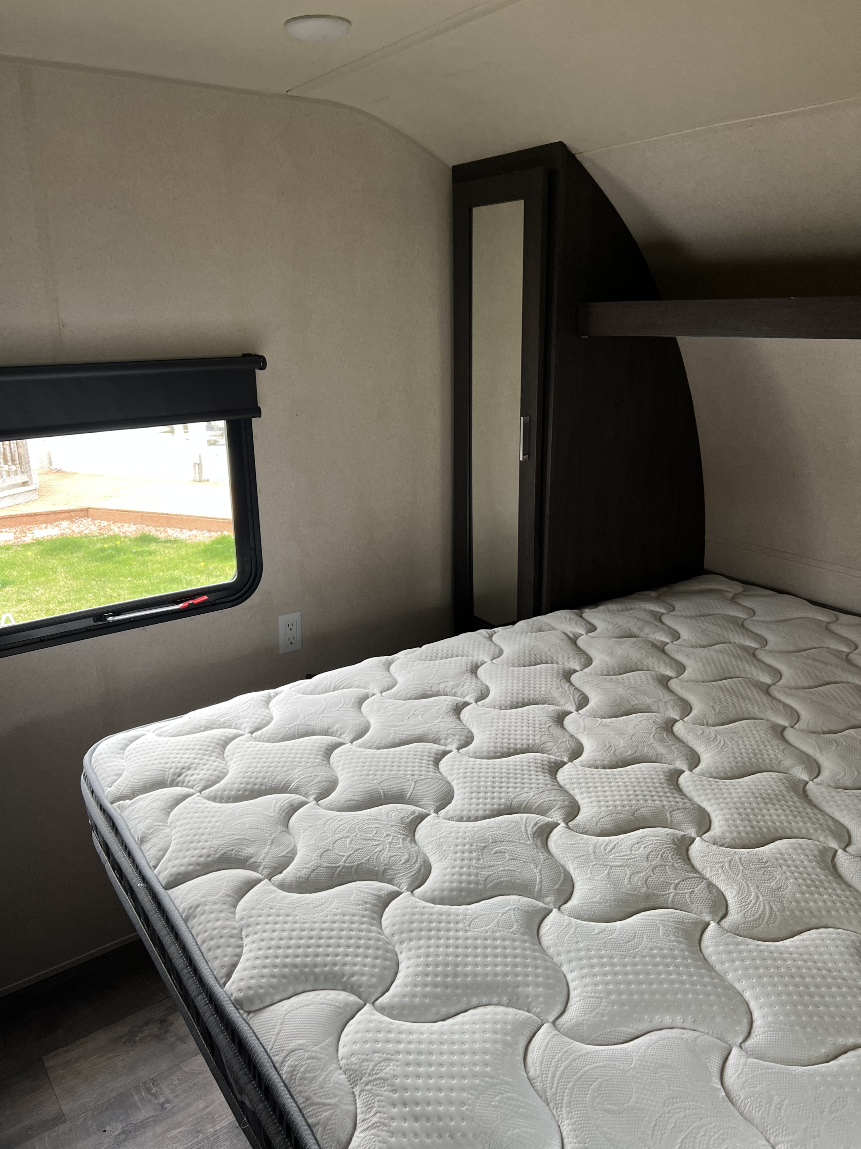 RV rental bedroom featuring a comfortable quilted mattress, window with outdoor view, and built-in storage.. Forest River Salem 2019