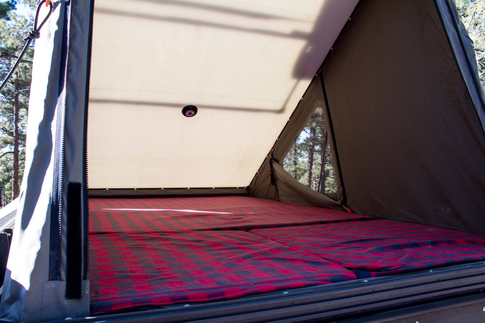 Cozy interior of an RV rental rooftop tent featuring a comfy plaid bed and views of the outdoors.. Dodge Ram PowerWagon 2500 6.4L HEMI 2020