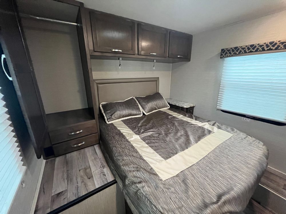 RV rental bedroom: comfortable bed, overhead cabinets, wardrobe, and window with emergency exit.. Jayco Redhawk 2021