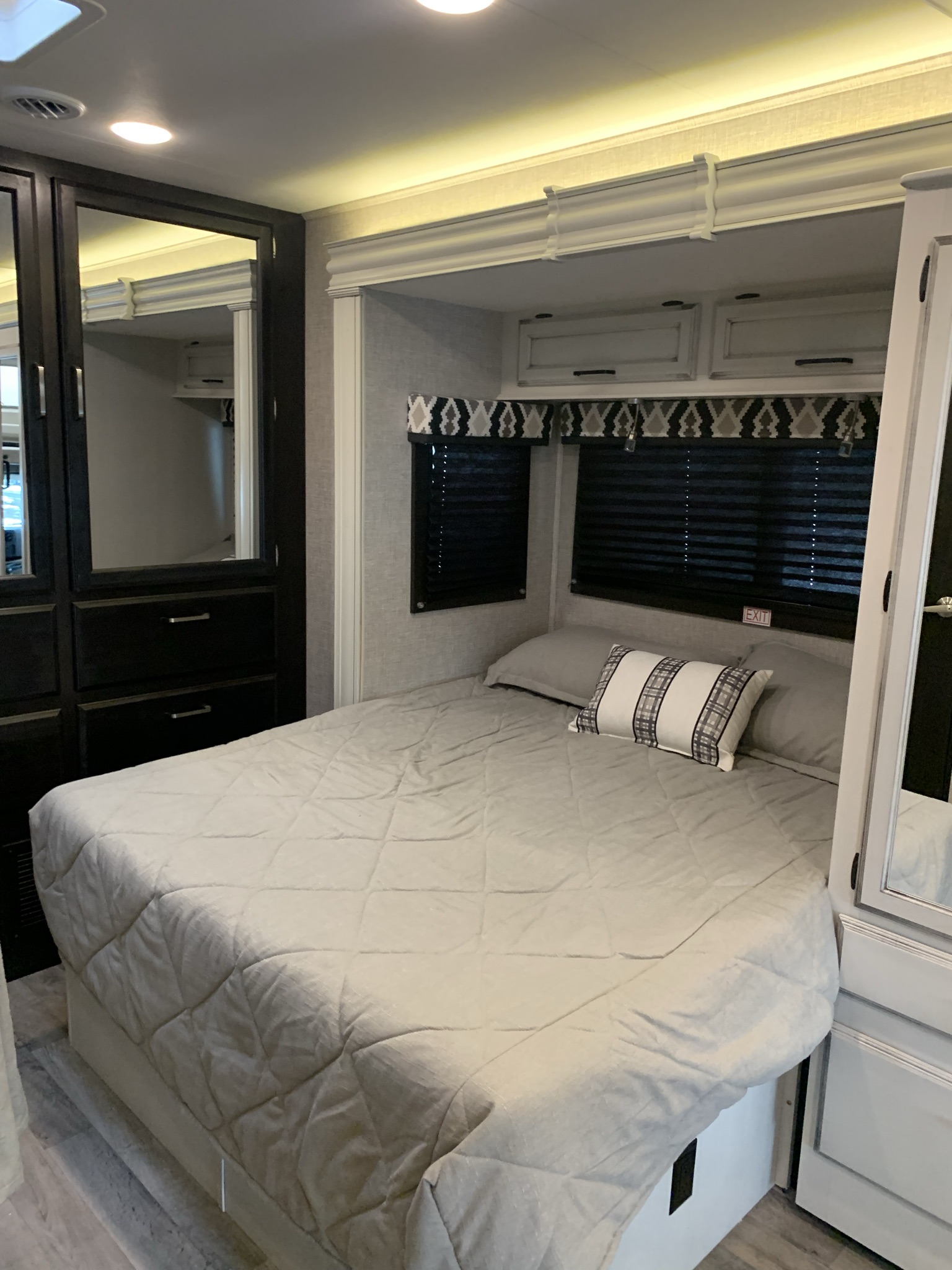 This RV rental bedroom features a comfy bed with light grey bedding, surrounding cabinets, and a compact design.. Entegra Odyssey 2022
