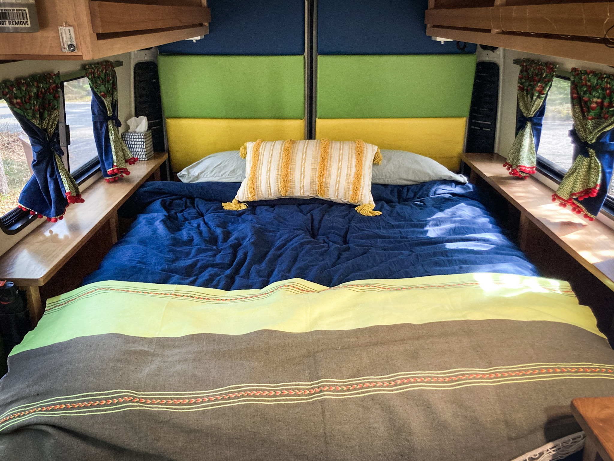 Cozy RV rental bedroom with colorful headboard, blue bedding, and berry-patterned curtains. Perfect for travel.. Dodge 1500 2016