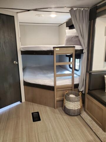 Inside an RV rental, two cozy bunk beds with white bedding offer a comfortable sleeping area for camping or travel adventures.. Keystone RV Hideout Luxury 2021