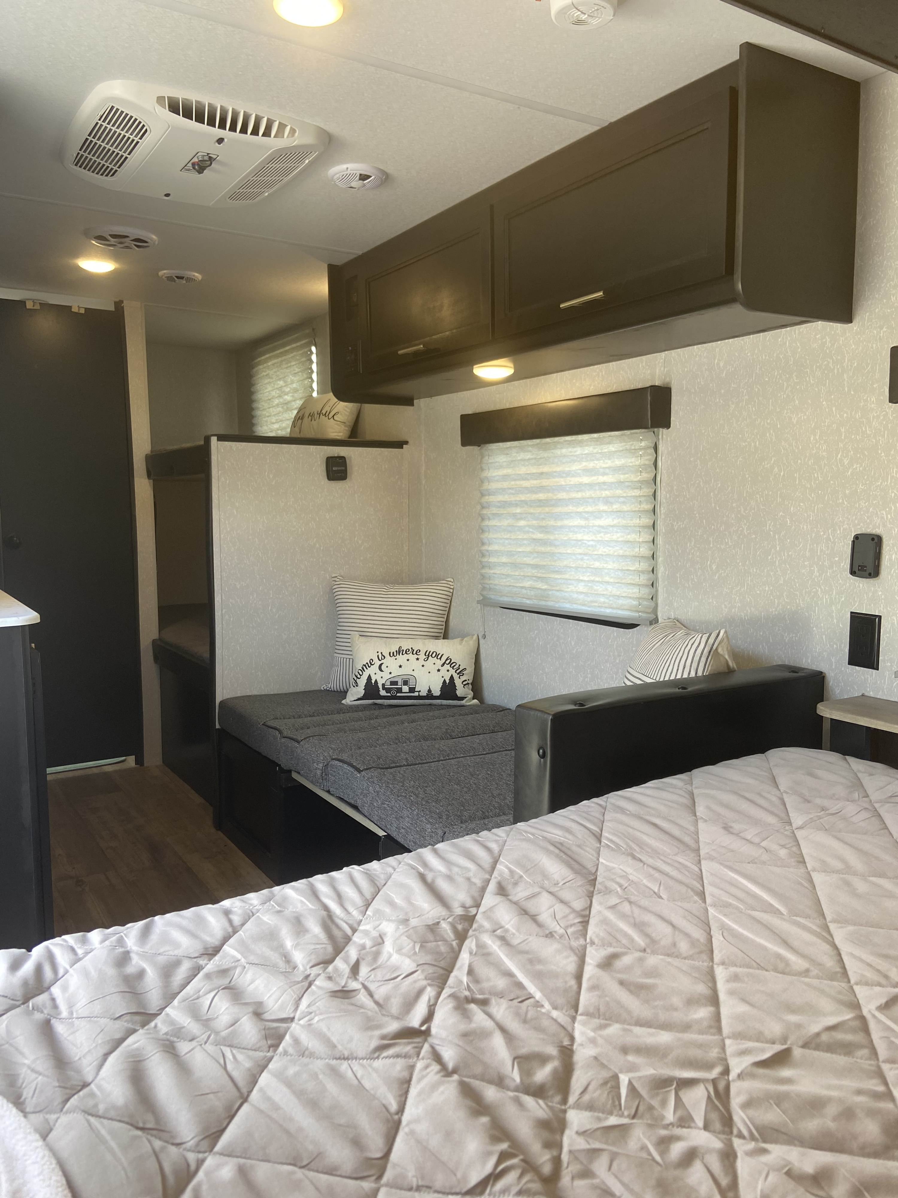 Cozy RV rental interior featuring a main bed, versatile sofa bed with custom pillow, and convenient bunk beds for comfortable travel.. Forest River Cherokee Wolf Pup 2022