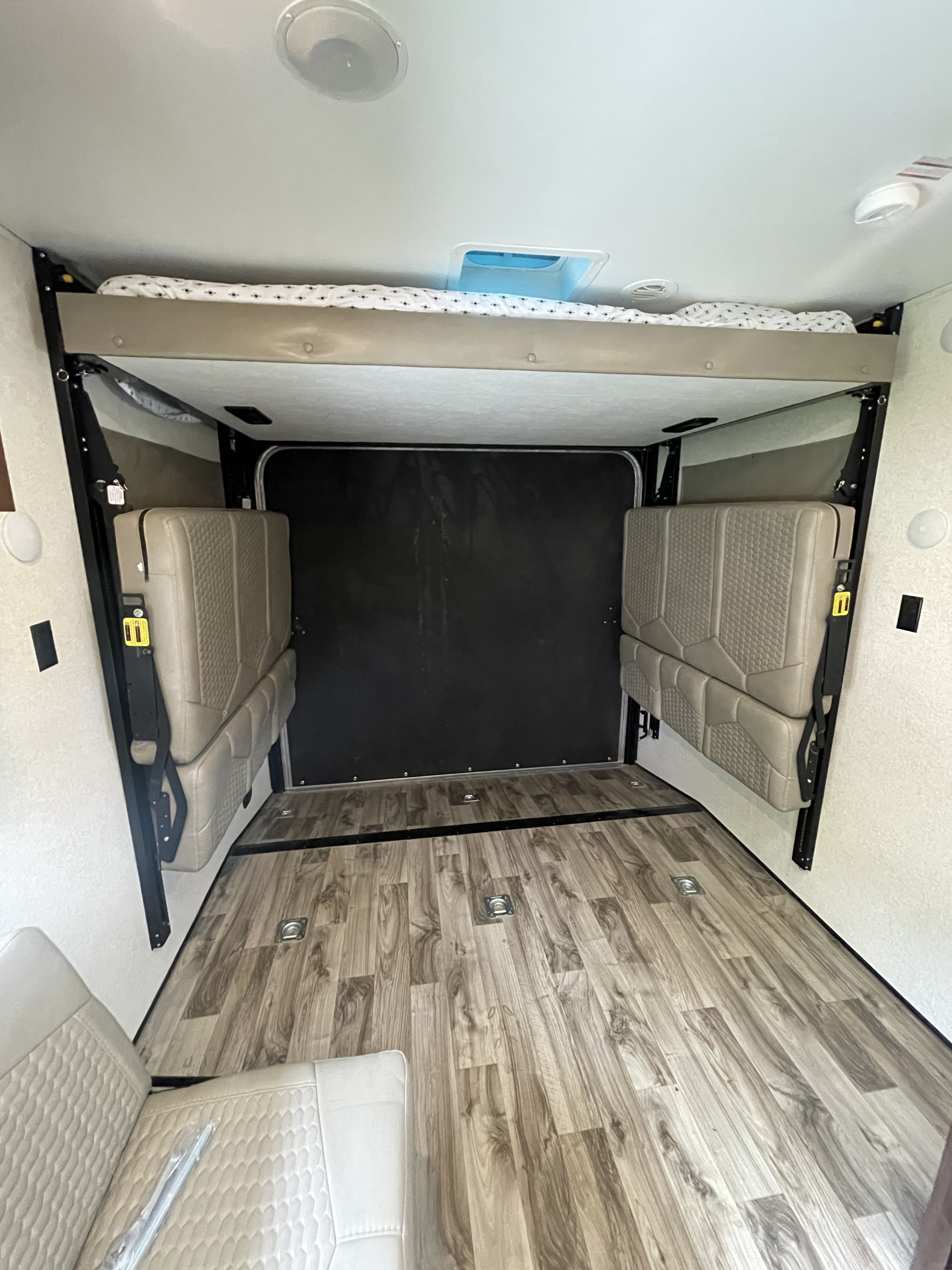 RV rental interior: A versatile garage area with an elevated bunk bed, folded seating, and durable wood-look flooring.. Jayco Octane 272 SL 2018