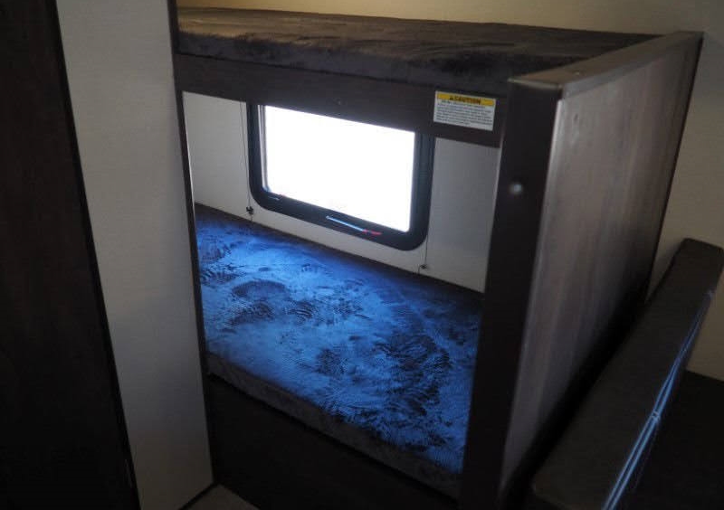 RV rental bunk beds: The lower bunk features a glowing blue mattress and a bright window; upper bunk is dark.. Coleman Coleman Lantern 2022