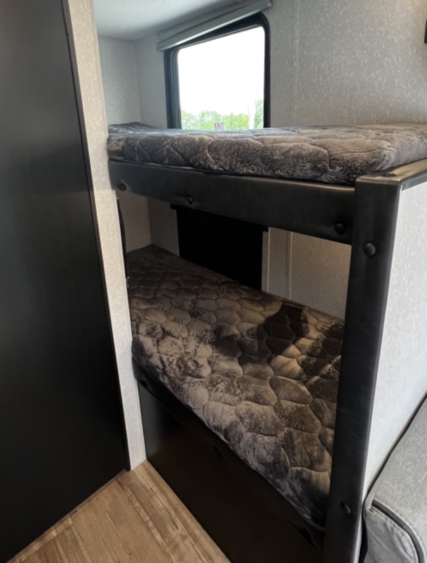 RV rental interior: stacked bunk beds with grey mattresses, providing compact sleeping space in this travel trailer.. Forest River Cherokee Wolf Pup Black Label 2022