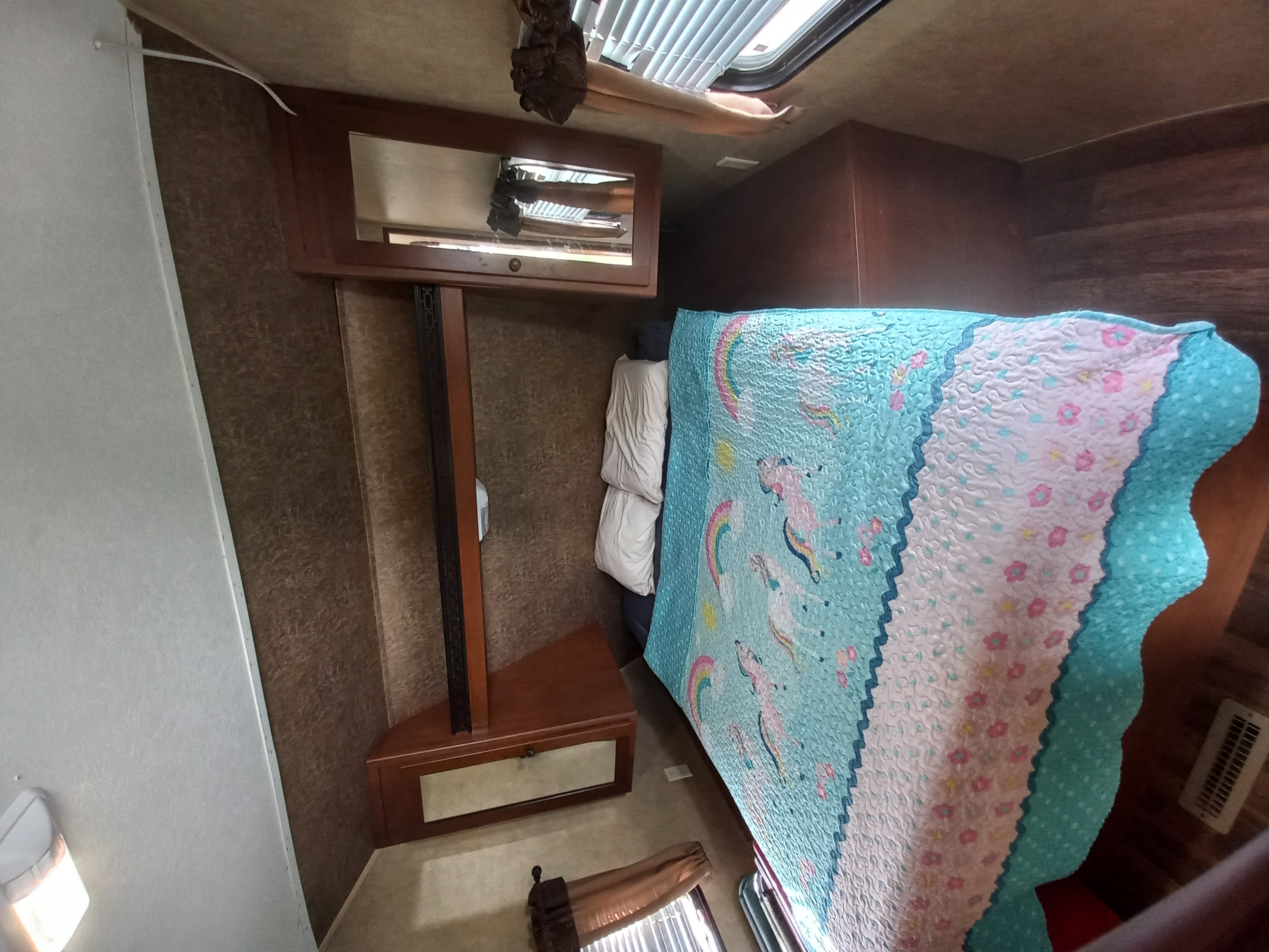 RV rental bedroom with a colorful unicorn comforter, built-in storage, and a ceiling skylight.. Aspen Trail Aspen Trail Trailer 2012
