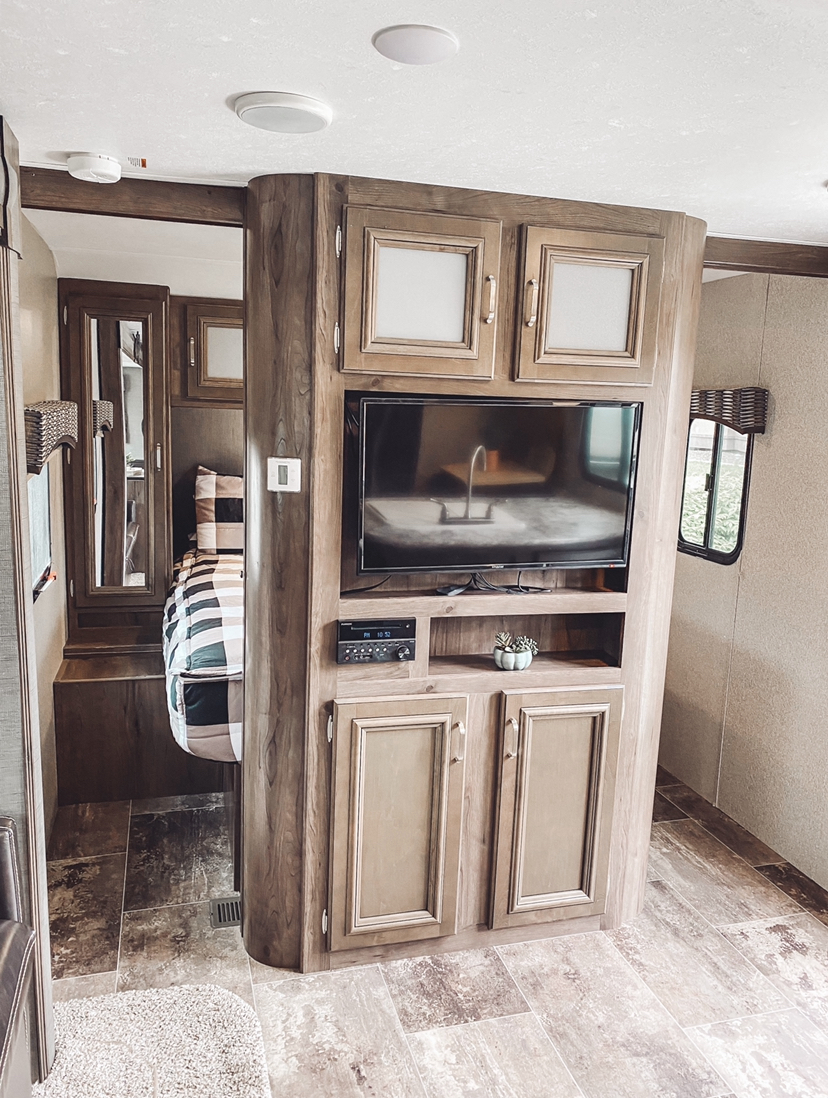 Modern RV rental interior: functional living space with entertainment center, sleek cabinetry, and cozy bedroom view.. Keystone RV Passport Ultra Lite 2018