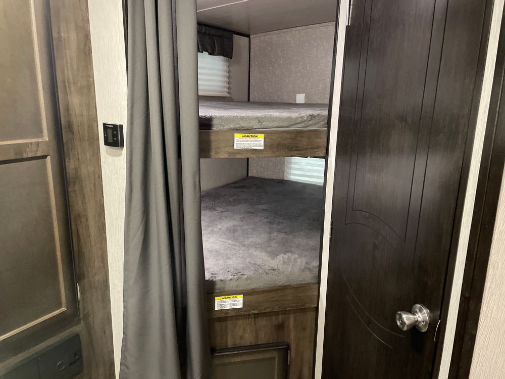 Inside an RV rental: view of the practical bunk bed area with two comfortable mattresses and a privacy curtain.. Heartland RVs Mallard 2020