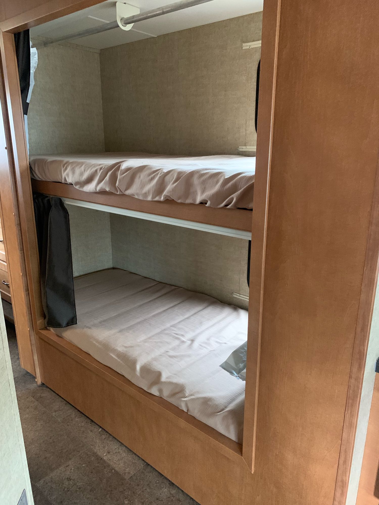 Compact bunk beds inside an RV rental, offering cozy sleeping for travelers. Features light bedding and wood accents.. Winnebago Minnie Winnie 2018