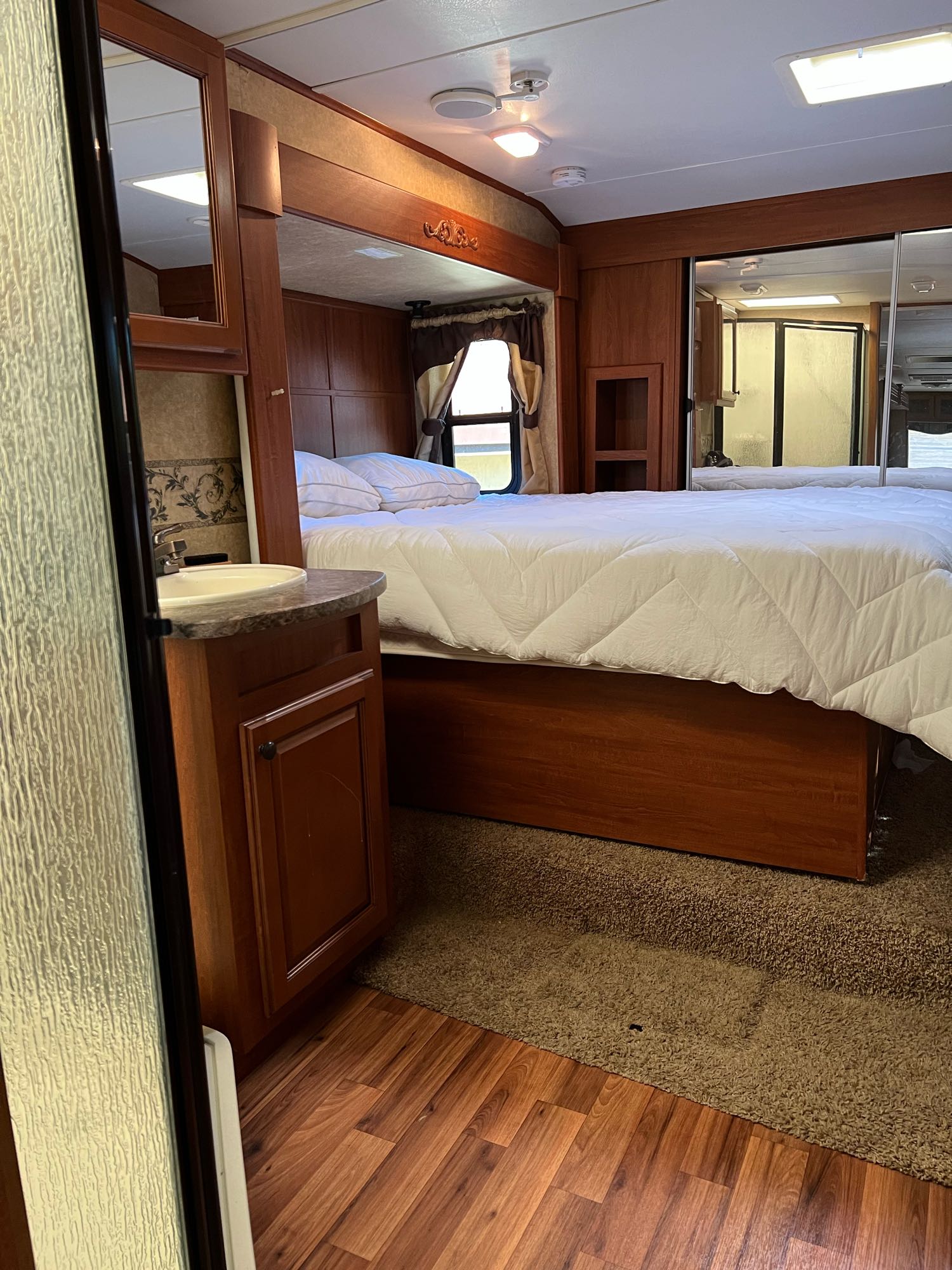 Comfortable RV rental bedroom with a queen bed, mirrored closet, and a convenient vanity sink for your travels.. Heartland Greystone 2011