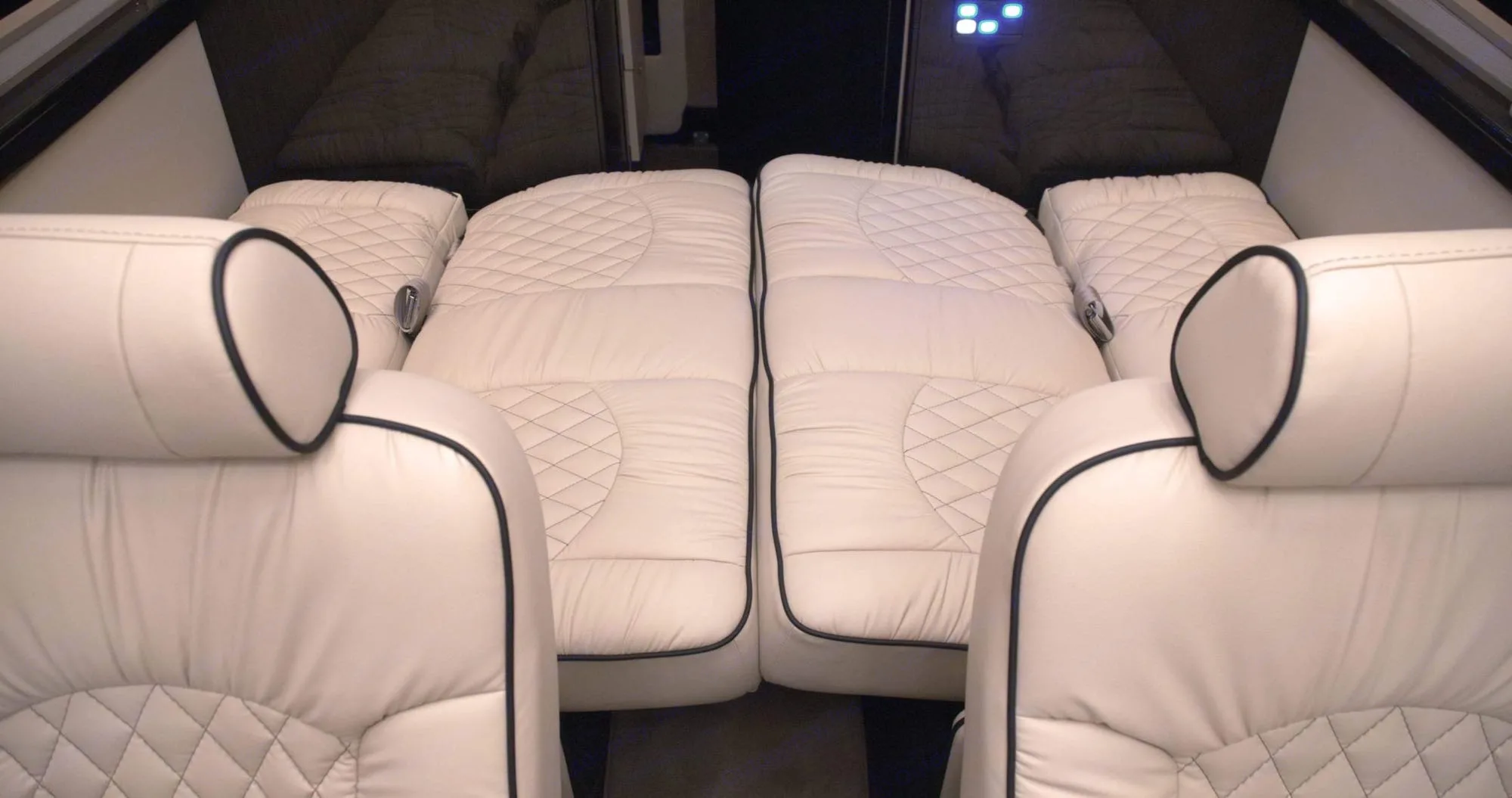 Luxurious RV rental interior shows cream, quilted leather beds & front seats, providing ultimate comfort for travel.. Ultimate Toys Ultimate Coach 2023