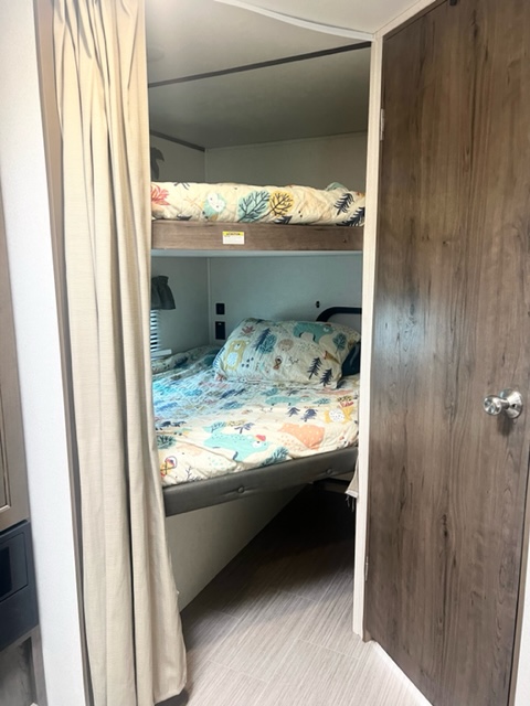 Inside an RV rental: view of comfortable bunk beds with colorful bedding, ideal for travel accommodation.. Keystone RV Passport SL 2020