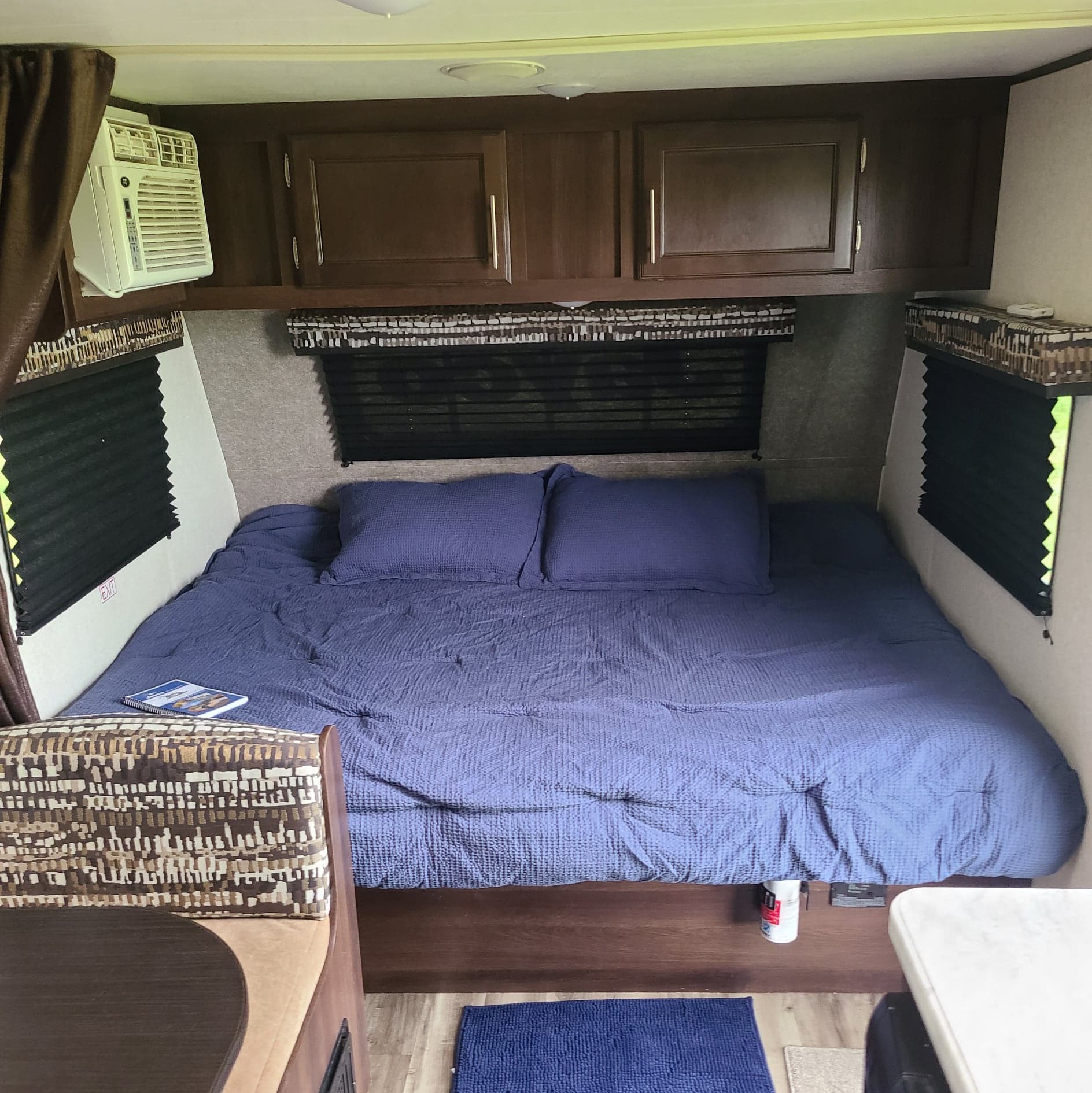 Comfortable RV rental bedroom featuring a blue bed, storage cabinets, and window AC unit for your travels.. Jayco Jay Flight SLX 2019