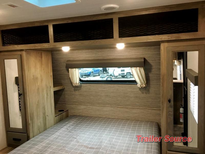 Inside this RV rental: a compact bedroom with bed, overhead storage, and mirrored wardrobe, providing comfort for travelers.. Forest River Surveyor Legend 2022
