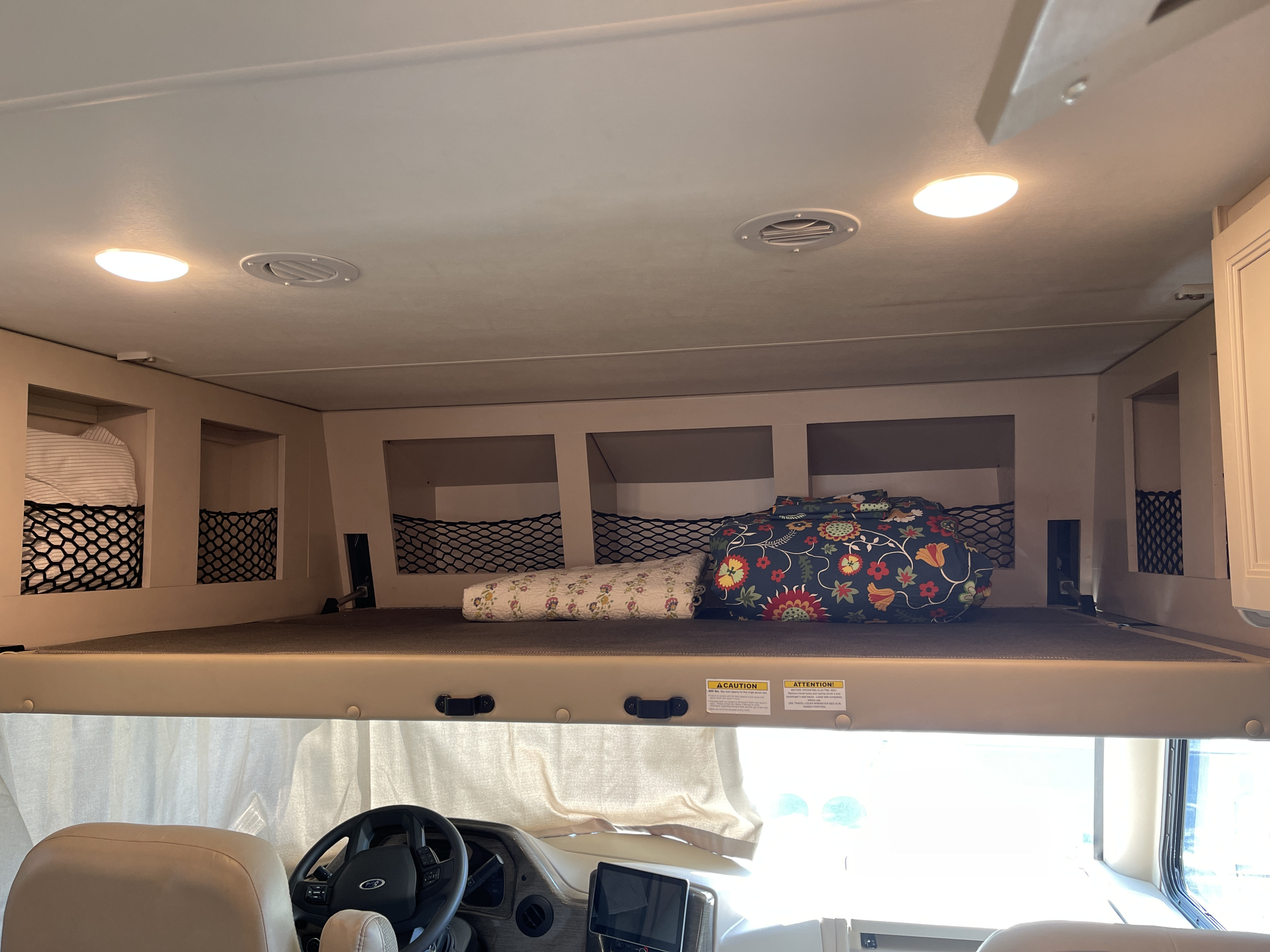 RV rental cab-over sleeping area, equipped with bedding, storage nets, lights, and air vents for guest comfort.. Thor A.C.E. 2022