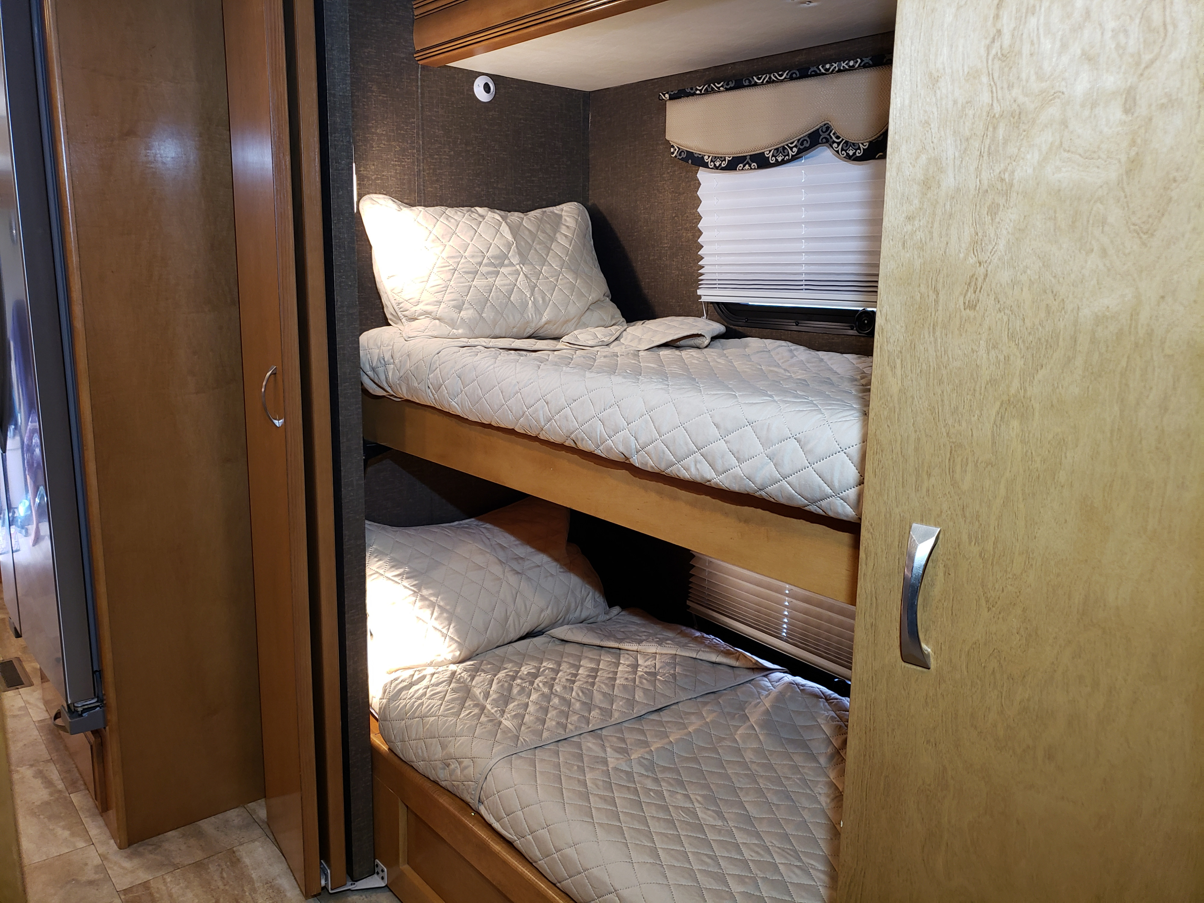 RV rental bunk beds: cozy, quilted bedding in a compact space, ideal for family travel.. Thor Challenger 2016