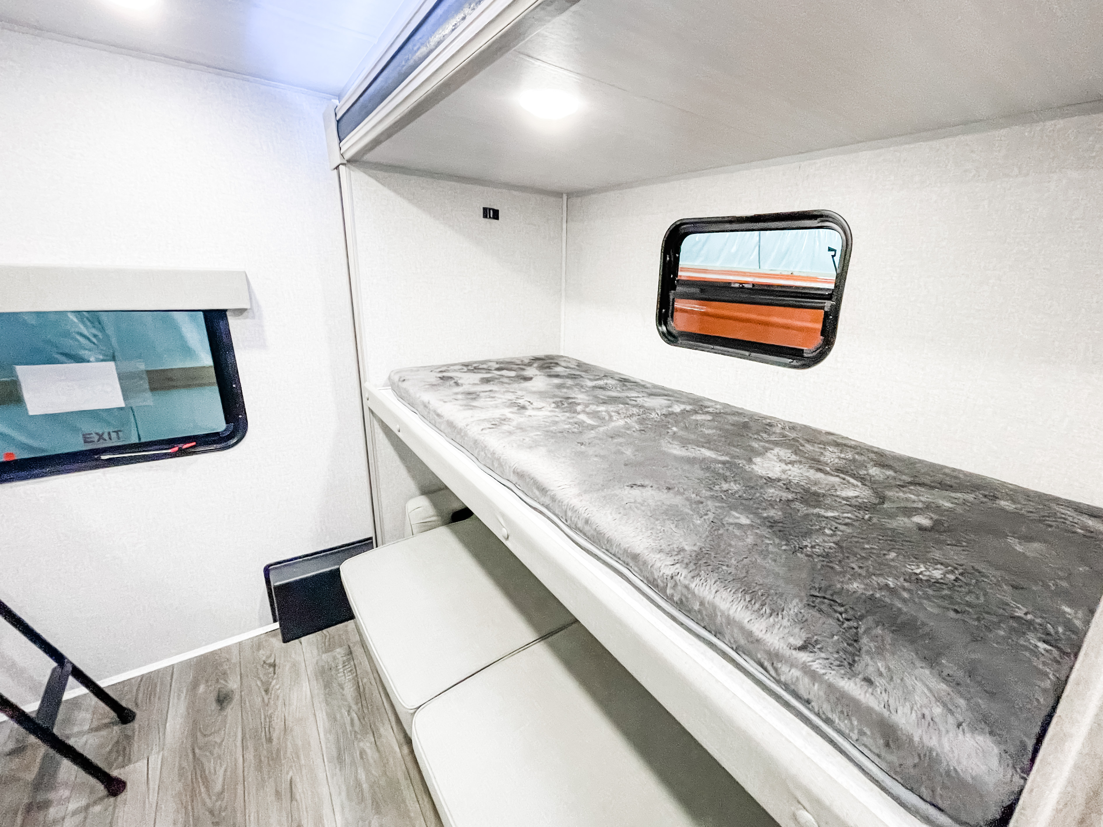 Bright RV rental interior with a cozy bunk bed and lower seating area, offering compact sleeping space.. East to West Alta 2022
