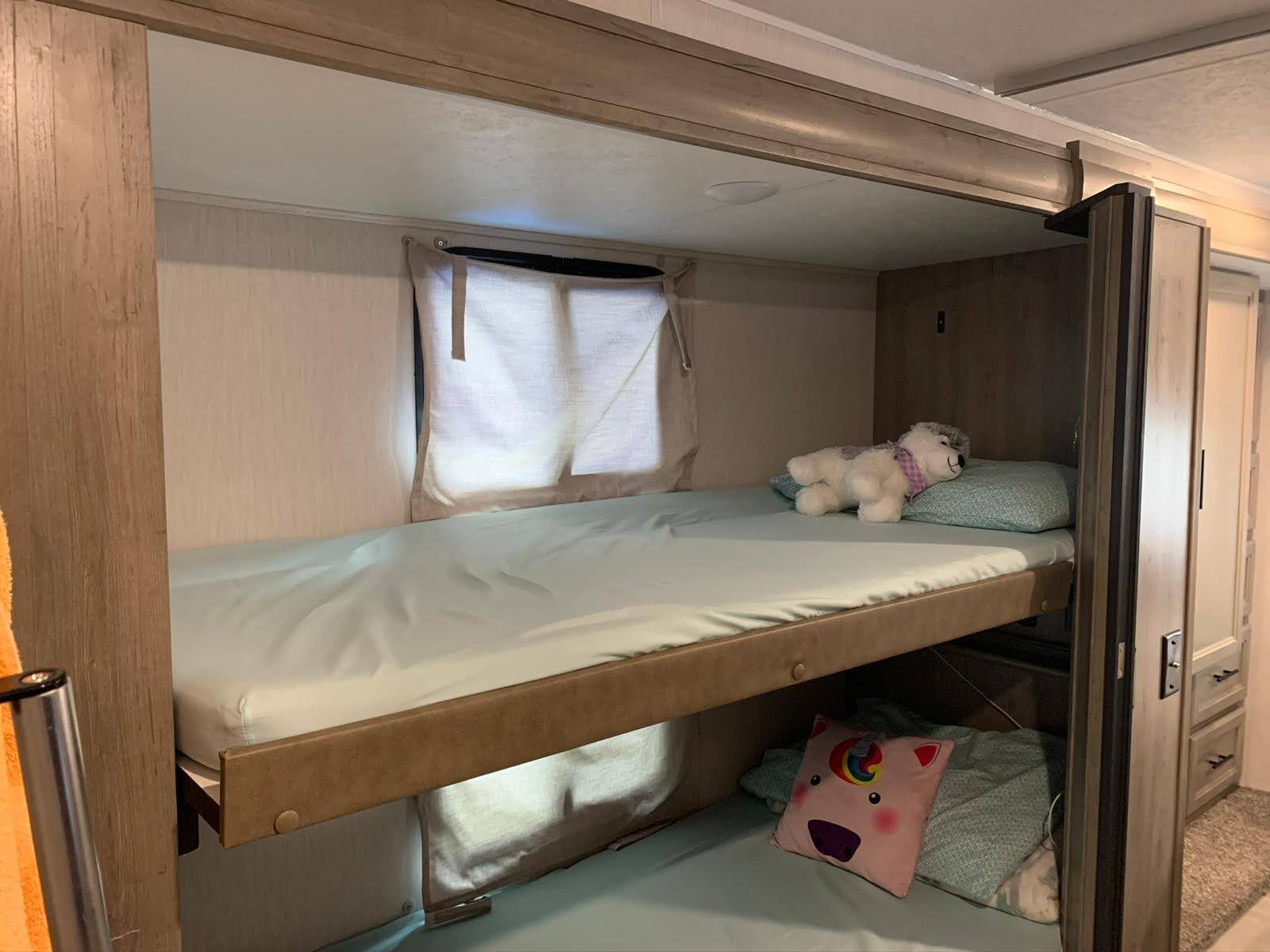 Cozy RV rental interior showing bunk beds with light blue sheets and stuffed animals, ideal for kids.. Forest River Coachmen Freelander Premier 2021