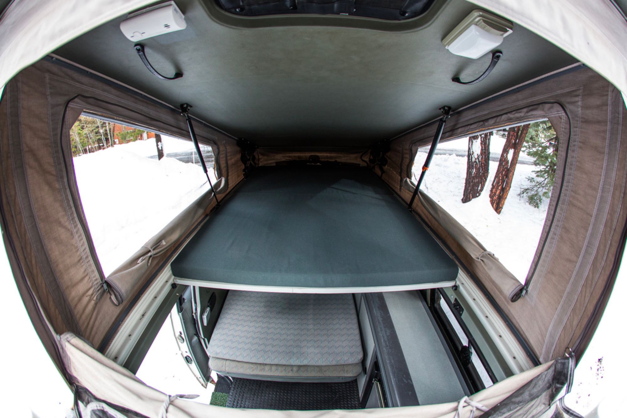 Inside an RV rental pop-top camper in winter, showing a sleeping area above and living space below.. Volkswagen Eurovan Camper 1999