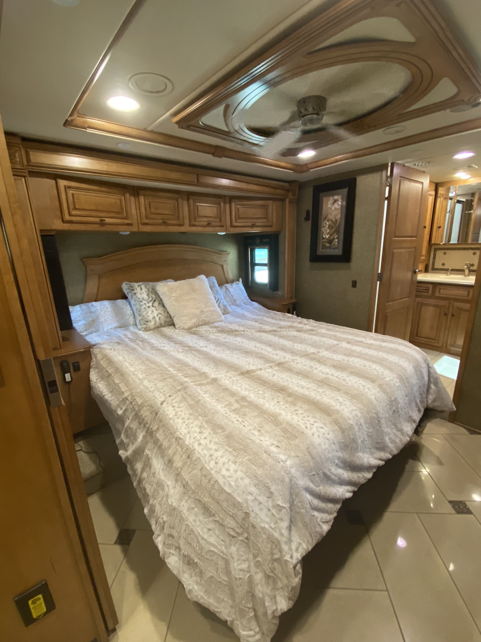 Spacious RV bedroom interior featuring a large bed, wooden cabinetry, and ceiling fan, ideal for any RV rental.. Winnebago Tour 2015