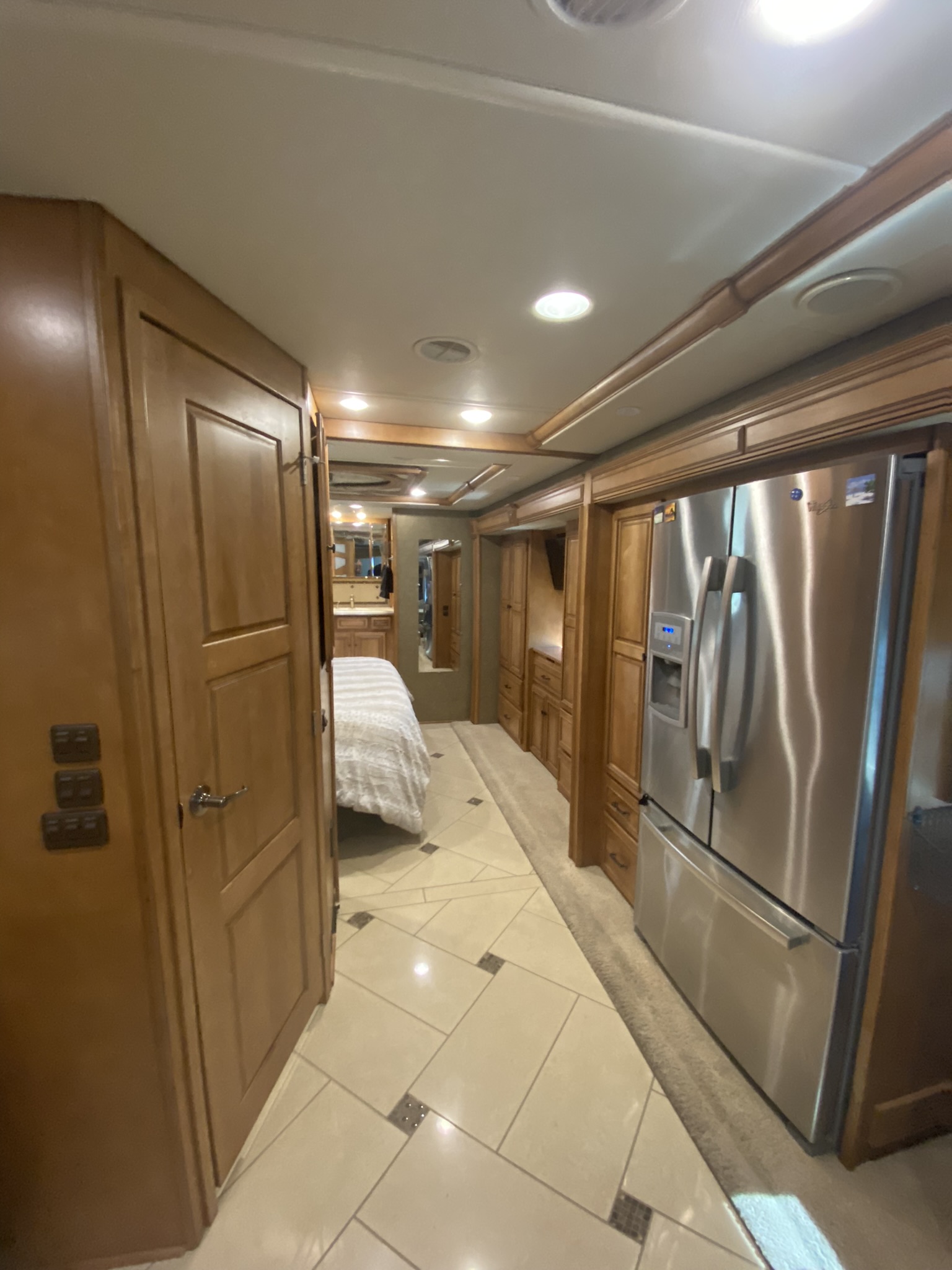 Explore this luxurious rv rental interior. Features a well-equipped kitchen with a large fridge, leading to a cozy bedroom.. Winnebago Tour 2015