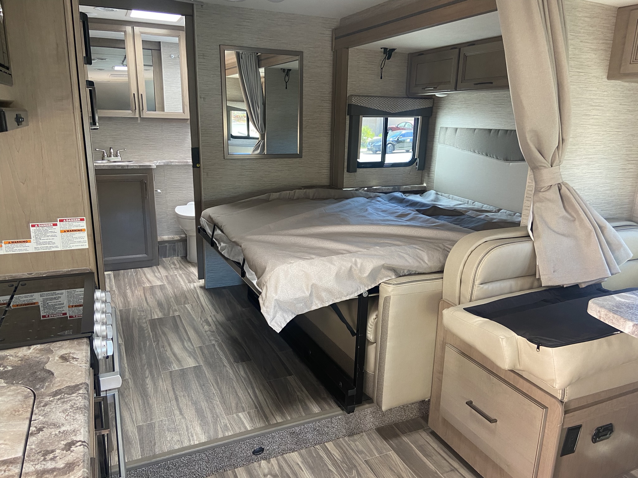 Modern RV rental interior: versatile living space with a pull-out bed, dining area, and compact kitchen/bath.. Thor Motor Coach Four Winds 25M 2022