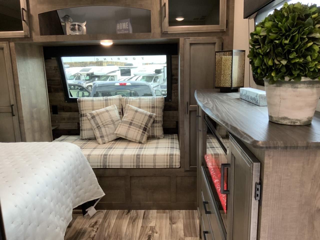 Inviting RV rental interior: plaid window seat, quilted bed, and decorative counter with a plant. Ready for adventure!. Venture Rv Sporttrek 2027