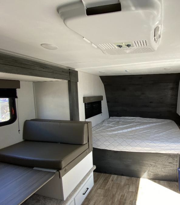 Inside this modern rv rental: a cozy bed, dinette seating, and AC for comfortable travels.. Keystone Hideout 2022