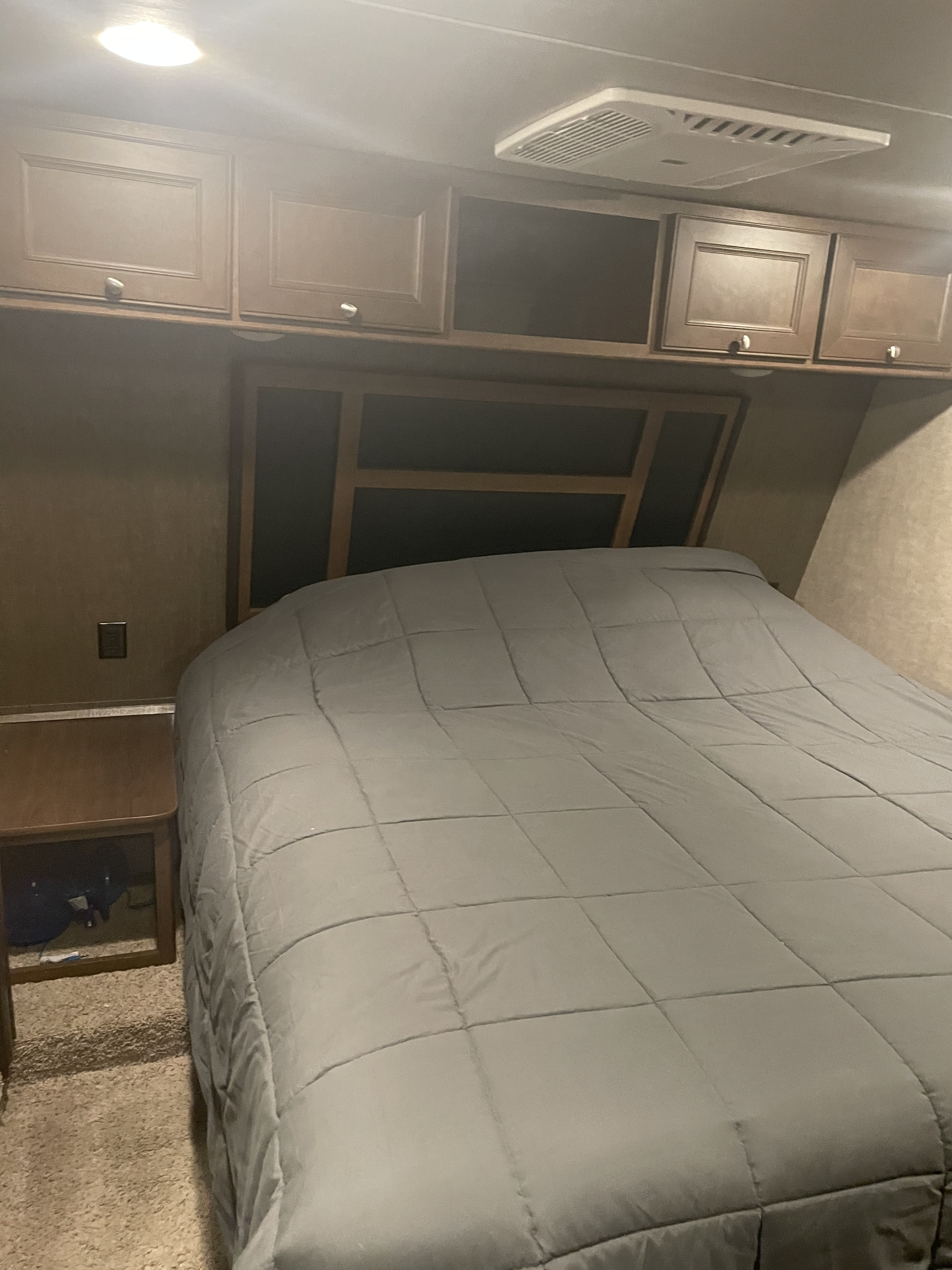 Cozy RV rental bedroom featuring a comfortable bed, overhead storage, and an AC unit for comfort.. Keystone Impact 2016